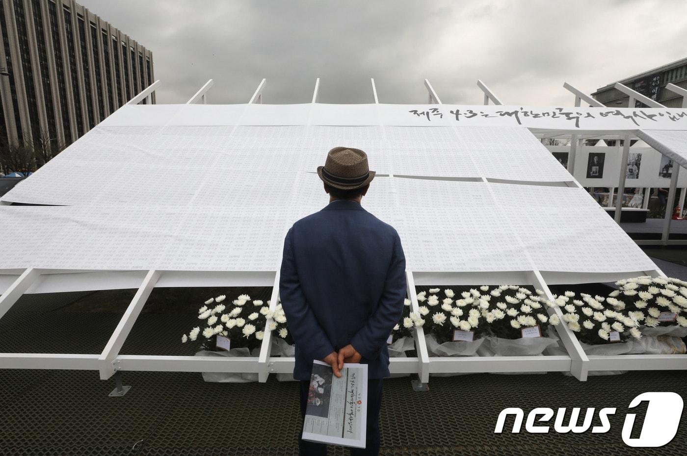 본문 이미지 - 한 시민이 3일 오전 서울 광화문광장에 마련된 제주 4‧3 추모공간을 찾아 희생자들의 이름을 살펴보고 있다. ⓒ 뉴스1 이광호 기자