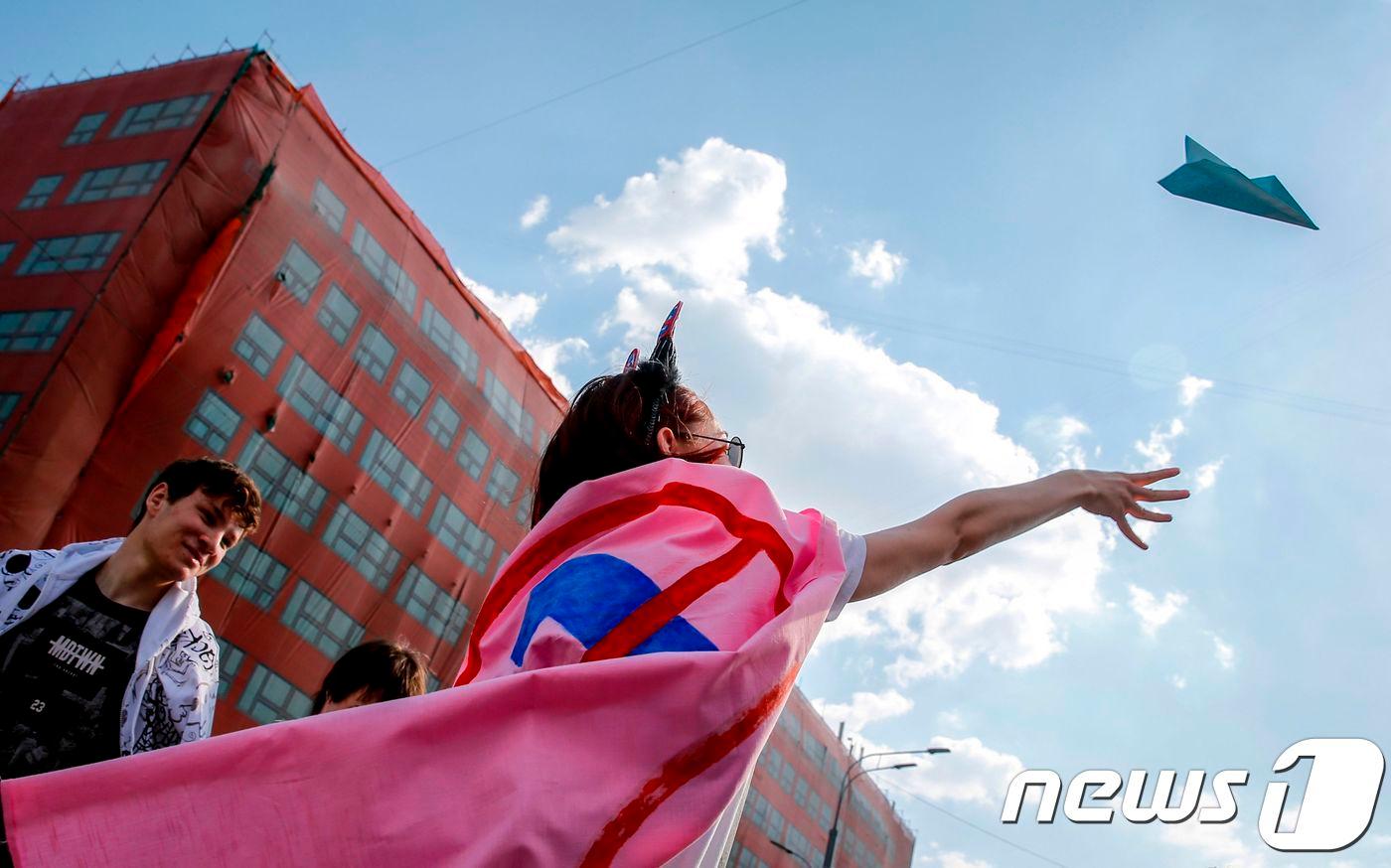 본문 이미지 - 러시아 모스크바에서 한 여성이 텔레그램 차단 중단 시위에 참석해 텔레그램의 상징인 종이 비행기를 공중에 날리고 있다. ⓒ AFP=뉴스1