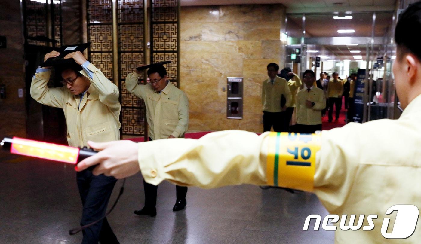 2018년 5월 16일 김성곤 국회 사무총장과 관계자들이 국민참여 지진 대피훈련 실시에 따라 서울 여의도 국회에서 머리를 보호하며 계단을 이용해 지하 대피소로 대피하고 있다. ⓒ News1 DB