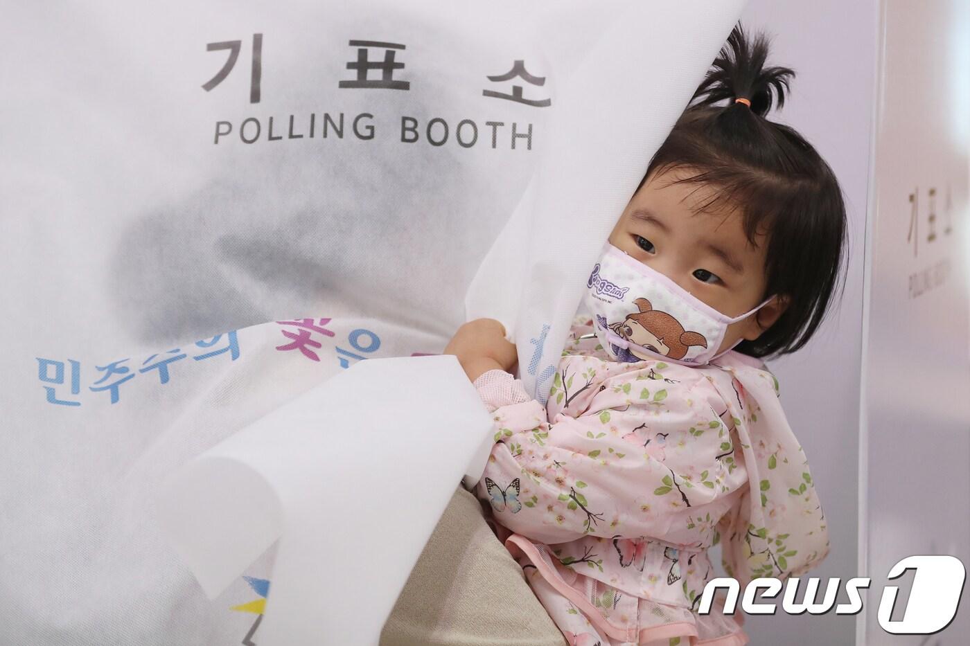 본문 이미지 - 6·13 지방선거 투표일인 13일 오전 대구 중구 남산3동행정복지센터에 마련된 남산3동 제1투표소에서 엄마 품에 안겨 기표소에 들어간 어린이가 밖을 내다보고 있다. 2018.6.13/뉴스1 ⓒ News1 공정식 기자