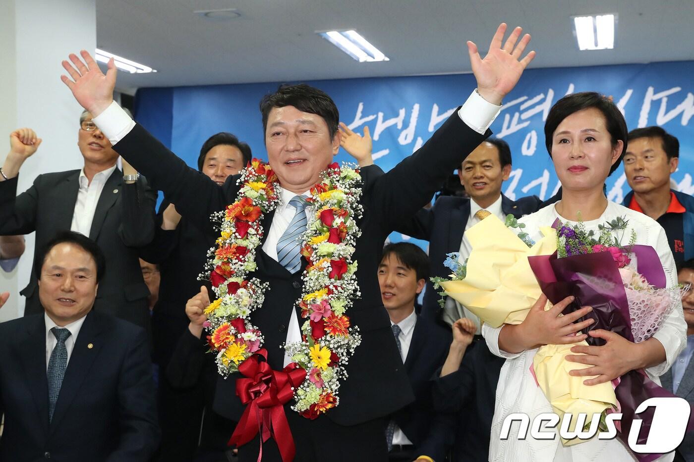 본문 이미지 - 최재성 더불어민주당 송파을 국회의원 후보가 13일 오후 서울 송파구 삼전로에 위치한 선거사무소에서 국회의원 재보궐선거 당선이 유력해지자 부인 황혜영과 함께 꽃목걸이를 목에 걸고 환하게 웃고 있다. 2018.6.13/뉴스1 ⓒ News1 임세영 기자
