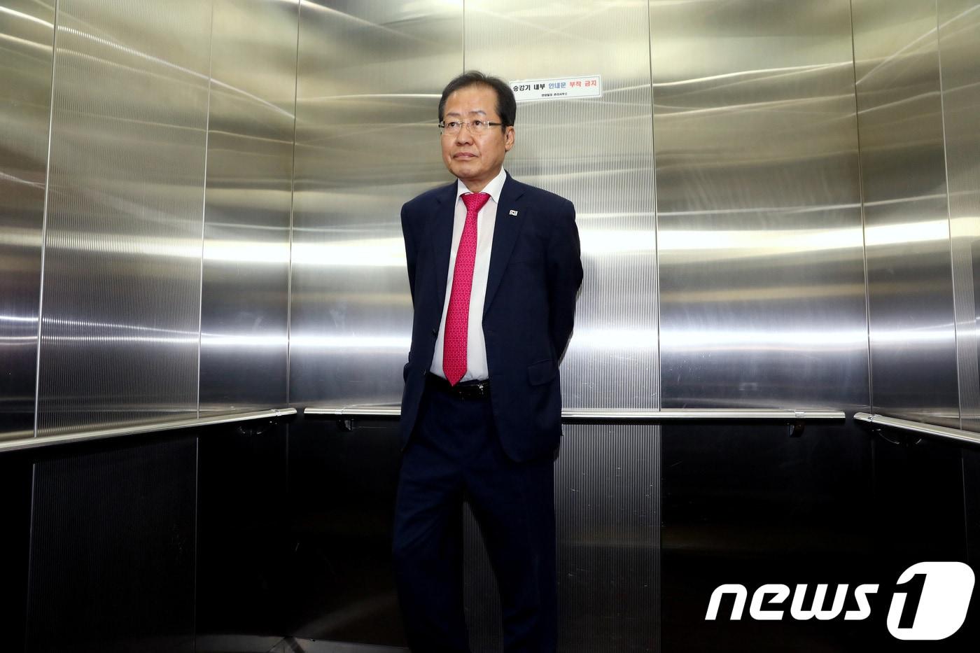 본문 이미지 - 2018년 6월 14일 홍준표 자유한국당 대표가 서울 여의도 당사에서 열린 최고위원회의에서 6.13 지방선거 참패 결과에 대해 대표직 사퇴를 공식 발표한 뒤 밖으로 나와 씁쓸한 표정으로 엘리베이터에 올라 있다. ⓒ News1 DB