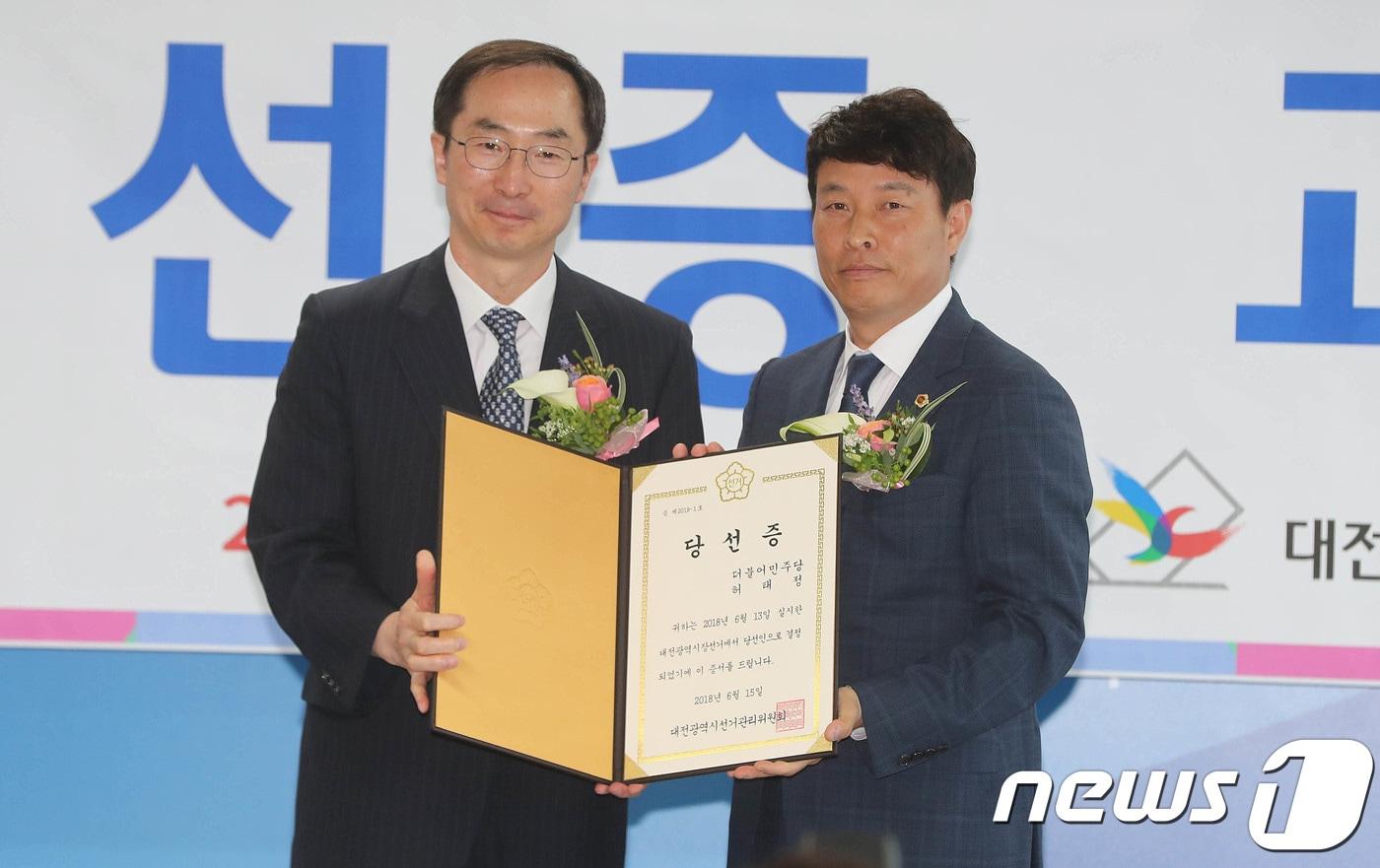 본문 이미지 - 6.13지방선거에서 당선된 허태정 대전시장 당선인의 대리인 전문학 더불어민주당 대전시 선거대책본부장(오른쪽)이 15일 오전 대전 선거관리위원회에서 열린 당선증 교부식에 참석해 김필곤 대전시선관위 위원장으로부터 당선증을 전달받고 있다. 2018.6.15/뉴스1 ⓒ News1 주기철 기자