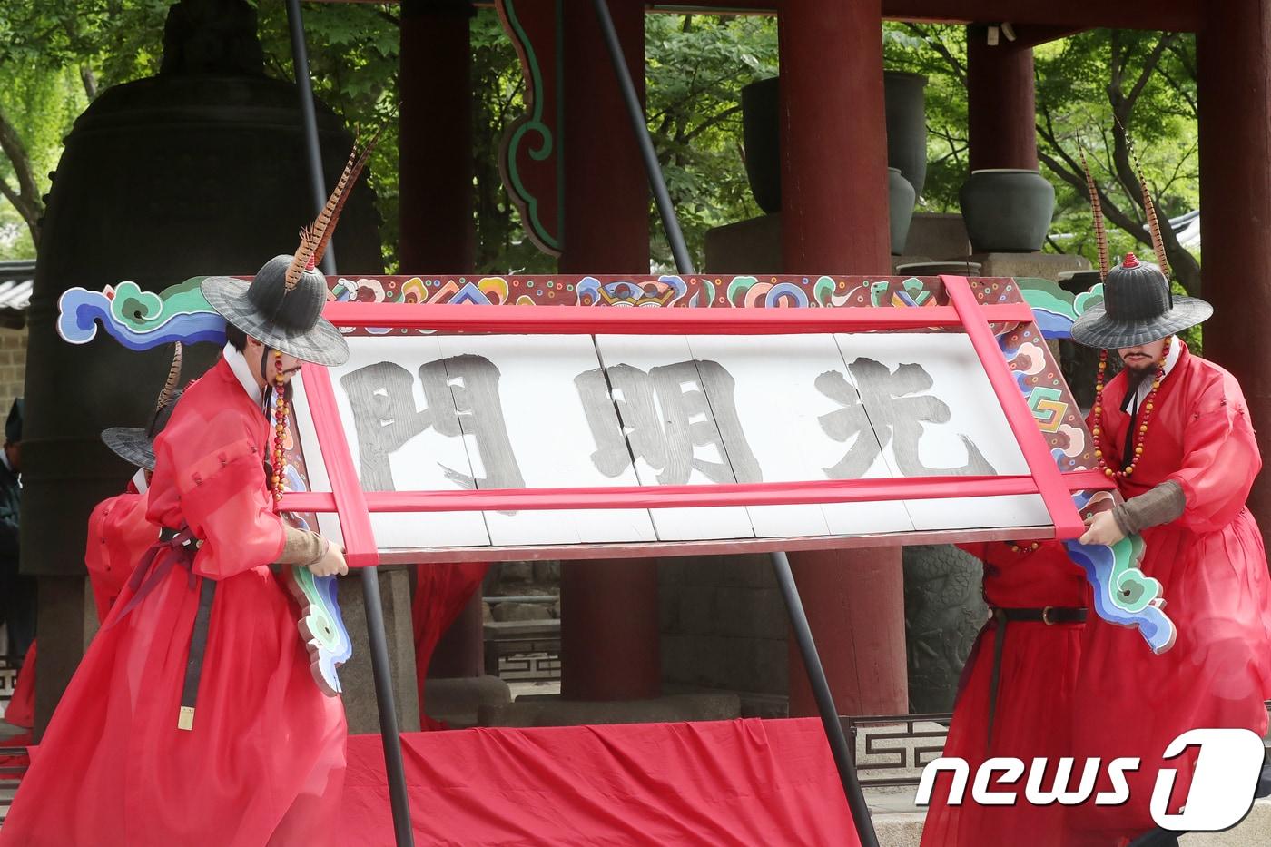 본문 이미지 - 19일 서울 중구 덕수궁 광명문 앞에서 열린 '광명문 제자리 찾기' 기공식에서 수문장들이 광명문 현판을 내려 옮기고 있다. 2018.6.19/뉴스1 ⓒ News1 민경석 기자
