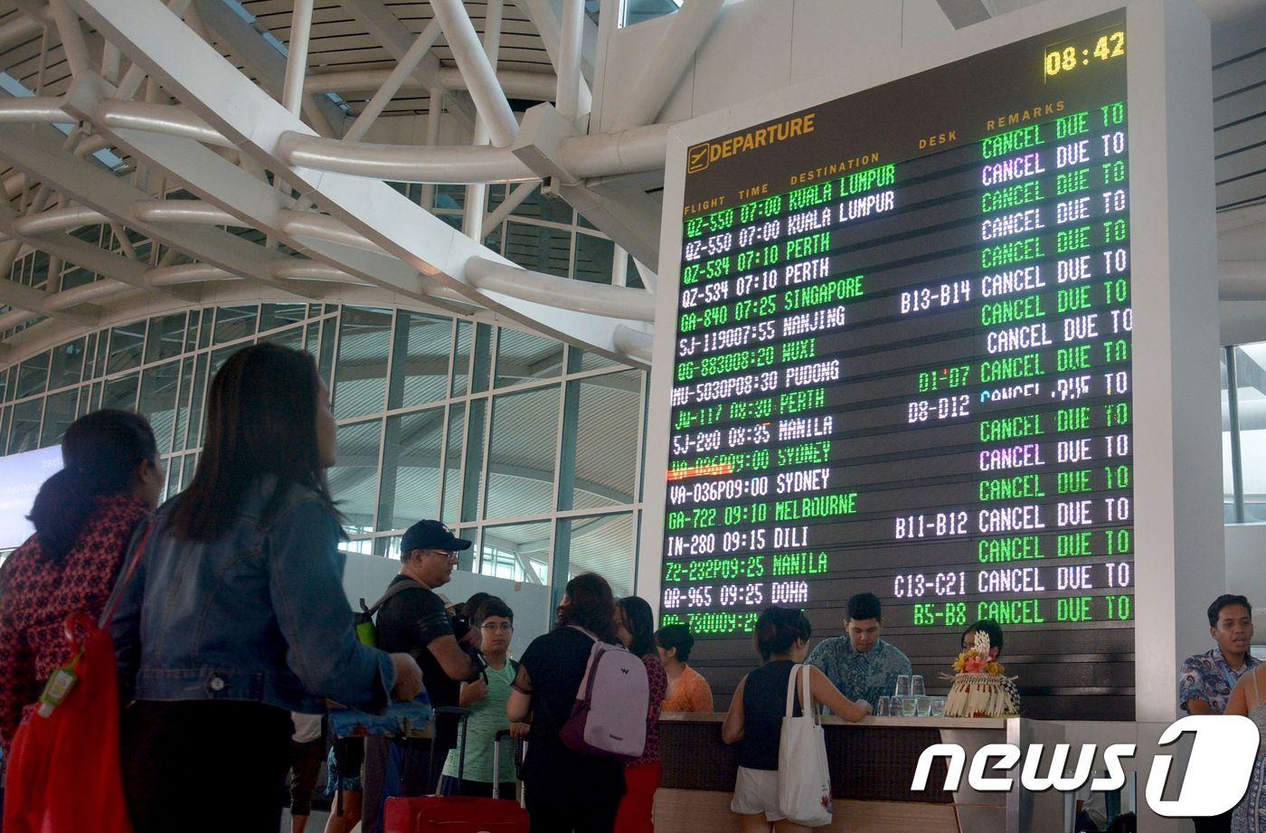 29일 응우라라이 공항에서 항공편 일정을 확인하고 있는 사람들 ⓒ AFP=뉴스1