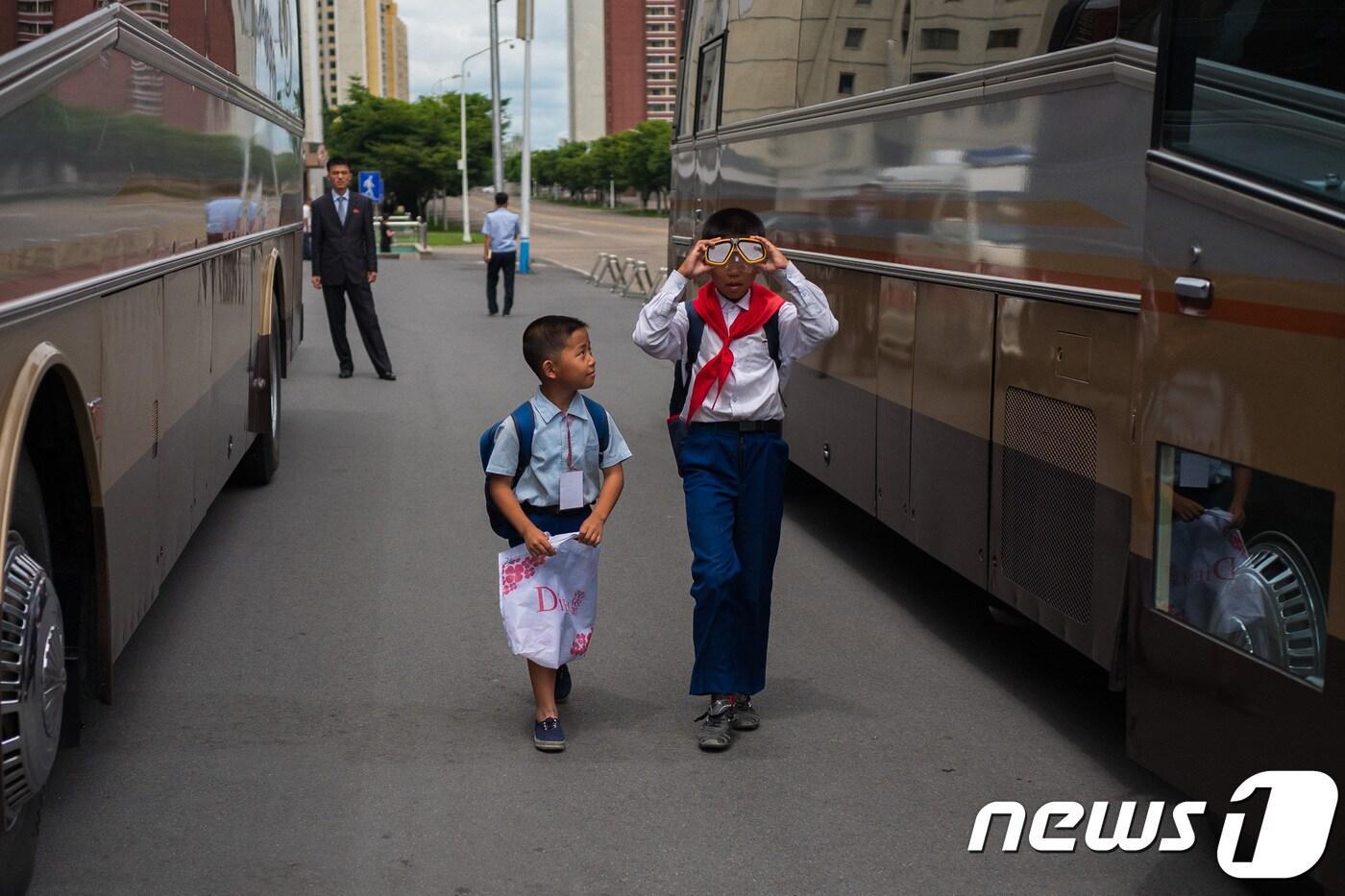 평양 고려호텔 앞에서 길을 가며 물안경을 써보는 학생과 그 모습을 바라보는 어린이 뒤로 북측 안내원의 모습. 2018.7.9/뉴스1 ⓒ News1 사진공동취재단