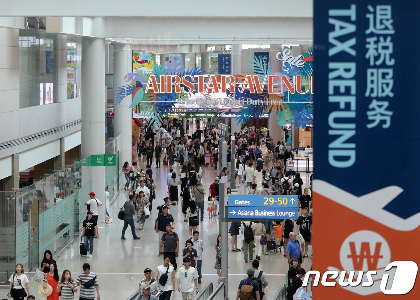 본문 이미지 - 13일 오후 인천국제공항 제1여객터미널 면세점이 여행객들로 북적이고 있다. 문재인 대통령은 이날 청와대에서 열린 수석·보좌관 회의에서 "입국장 면세점을 도입하자는 여론이 많다＂며 관계부처에 입국장 면세점 도입방안을 검토해달라고 주문했다. 2018.8.13/뉴스1 ⓒ News1 구윤성 기자