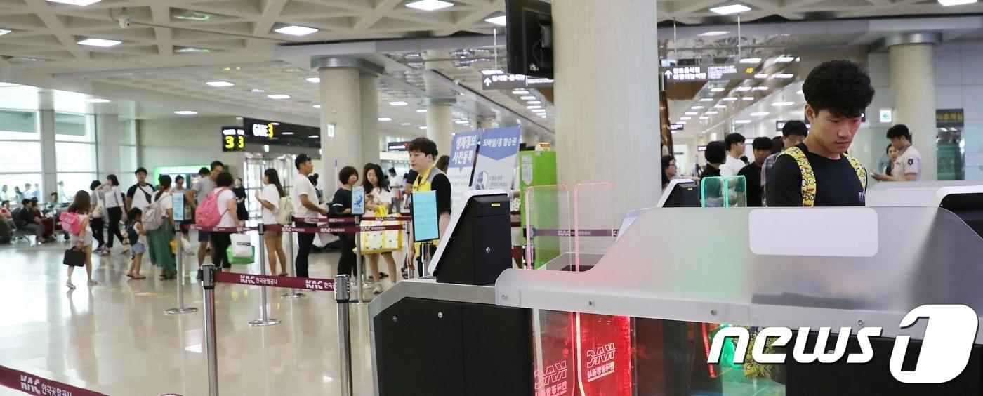 본문 이미지 - 14일 오전 한 관광객이 생체정보인식시스템을 이용해 출발장 안으로 들어가고 있다. 뒤편에 신원 확인을 기다리며 길게 늘어선 줄과는 대조적인 풍경이다. 2018.08.14/뉴스1 ⓒ News1 안서연 기자