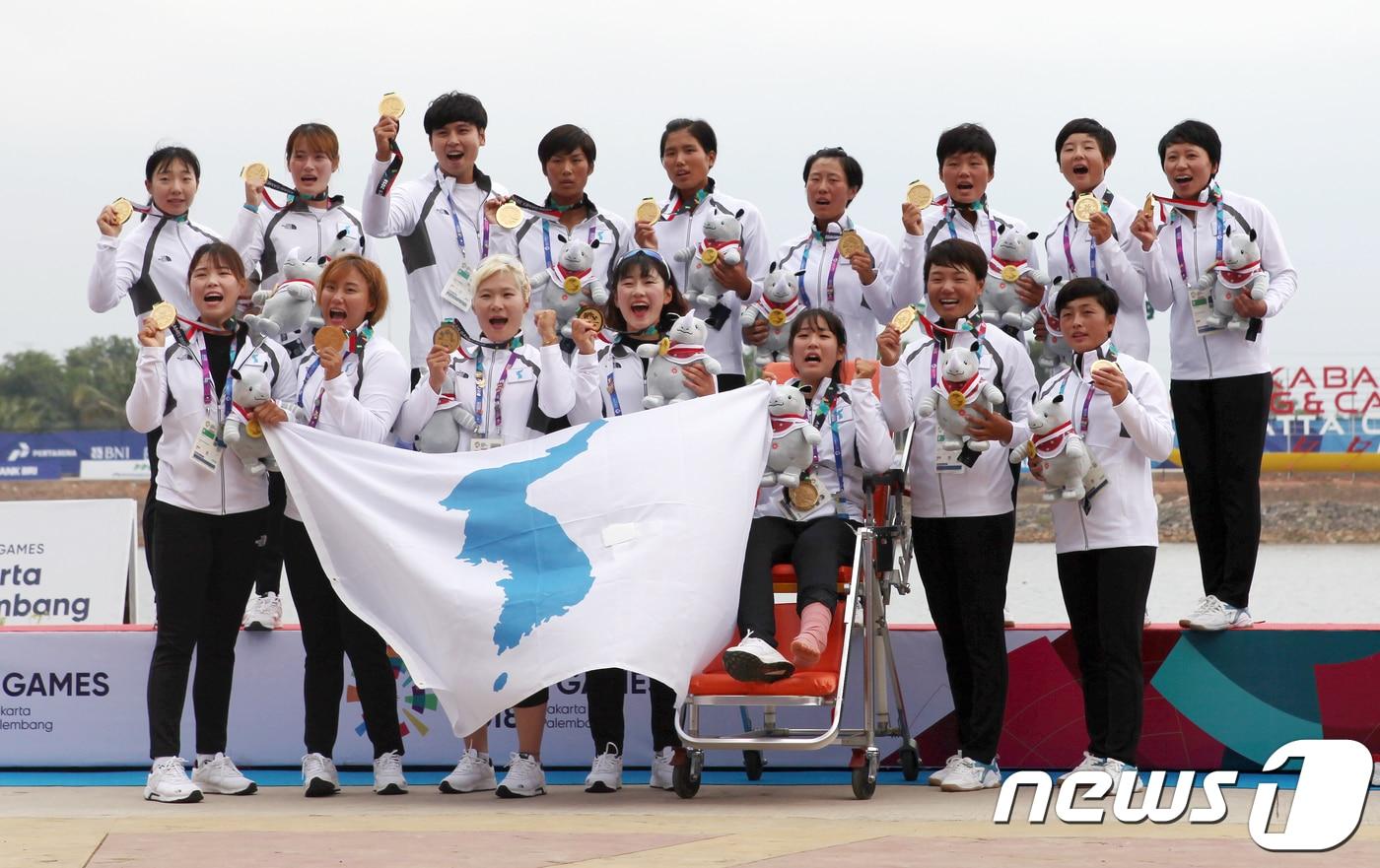 26일 인도네시아 팔렘방 자카바링 스포츠 시티 조정‧카누 레가타 코스에서 열린 2018 자카르타-팔렘방 아시안게임 500m 결선 메달 시상식에서 여자 카누 용선 남북 단일팀이 금메달을 목에 걸고 한반도기를 흔들고 있다. 단일팀은 이날 경기에서 중국과 태국을 제치고 2분24초788로 가장 먼저 결승선을 통과해 남북 단일팀으로는 처음 금메달을 획득했다. (대한카누연맹 제공) 2018.8.26/뉴스1