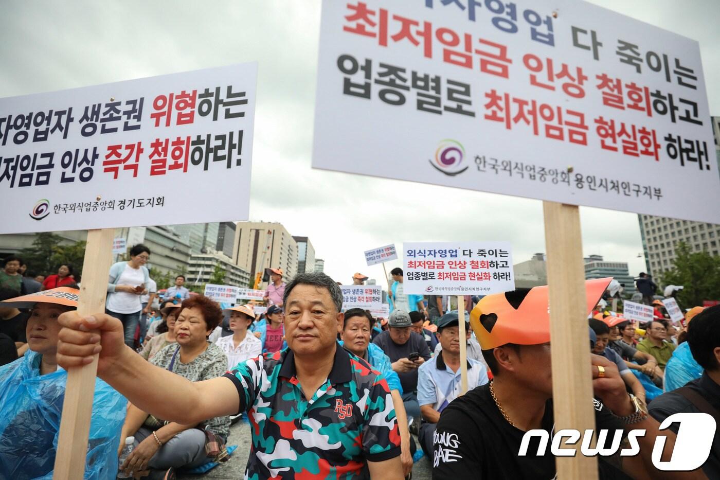 29일 서울 광화문광장에서 열린 소상공인 생존권 운동연대 주최 ‘최저임금 제도개선 촉구 국민대회’에서 참가자들이 최저임금 인상 철회를 주장하며 손피켓을 들고 있다. 2018.8.29/뉴스1 ⓒ News1 성동훈 기자