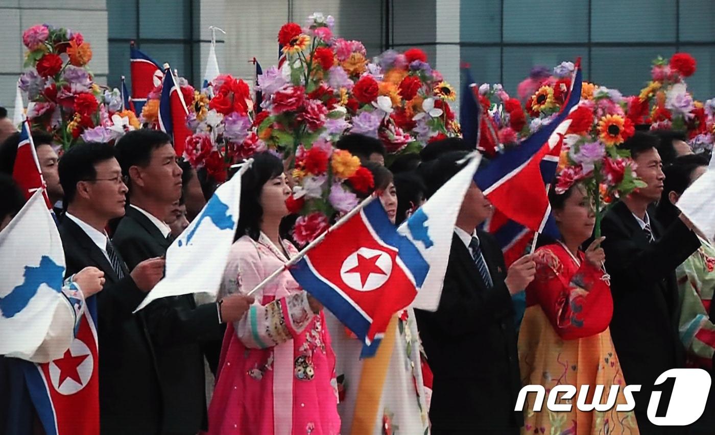 18일 오전 문재인 대통령의 평양 순안공항도착을 환영하기위해 한반도기와 인공기를 든 평양시민들의 모습이 서울 중구 동대문디자인플라자에 마련된 메인프레스센터에 문재인 대통령과 생중계 되고 있다. 2018.9.18/뉴스1 ⓒ News1 송원영 기자
