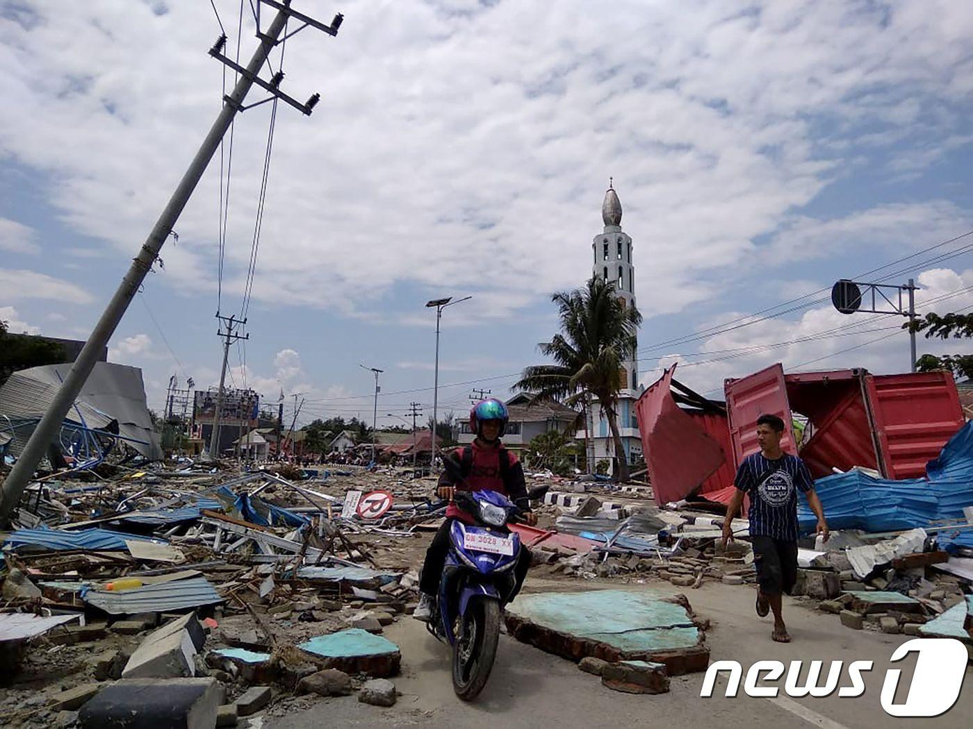 본문 이미지 - 29일 인도네시아 중부 술라웨시 섬 팔루에서 주민들이 강진과 쓰나미로 무너진 건물 잔해를 살펴보고 있다. 2018.9.29AFP/뉴스1 ⓒ AFP=뉴스1