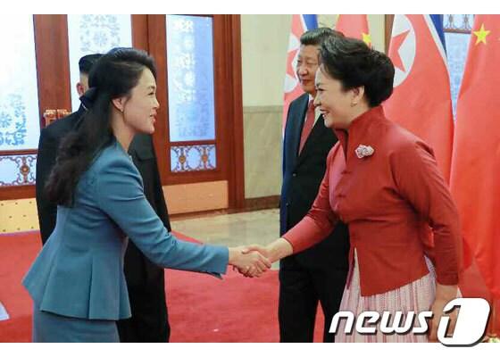 본문 이미지 - 리설주 여사(왼쪽) 펑리위안 여사가 중국 인민대회당에서 인사를 나누고 있는 모습. (노동신문) / 뉴스1
