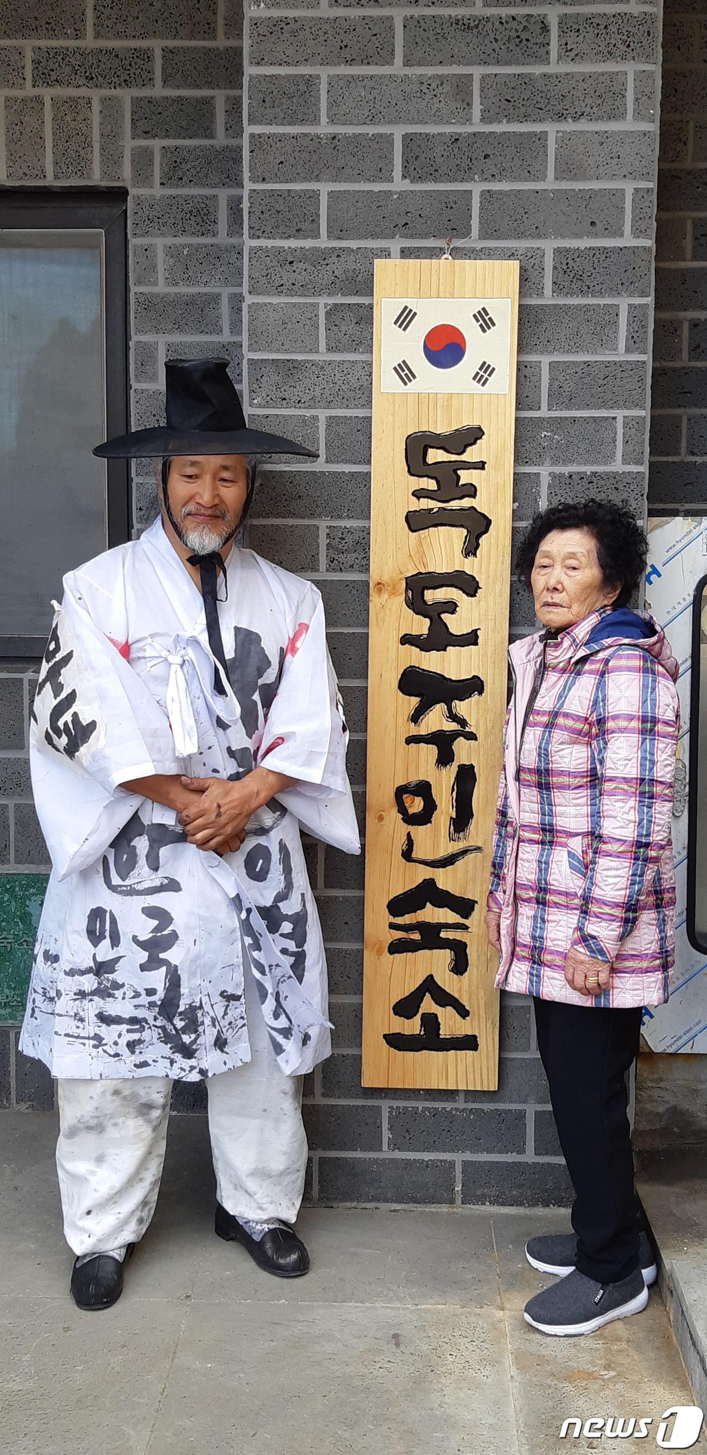 본문 이미지 - 2019년 10월 17일  고 김신열 씨(오른쪽)와 서예가 김동욱 씨(독도사랑예술인협회장)가 경북 울릉군 독도리 독도 주민숙소 현판식을 갖고 있다. 독도주민숙소 현판은 김동욱 씨가 직접 제작했다.(서예가 김동욱씨 제공) 2019.10.17 ⓒ 뉴스1 최창호 기자