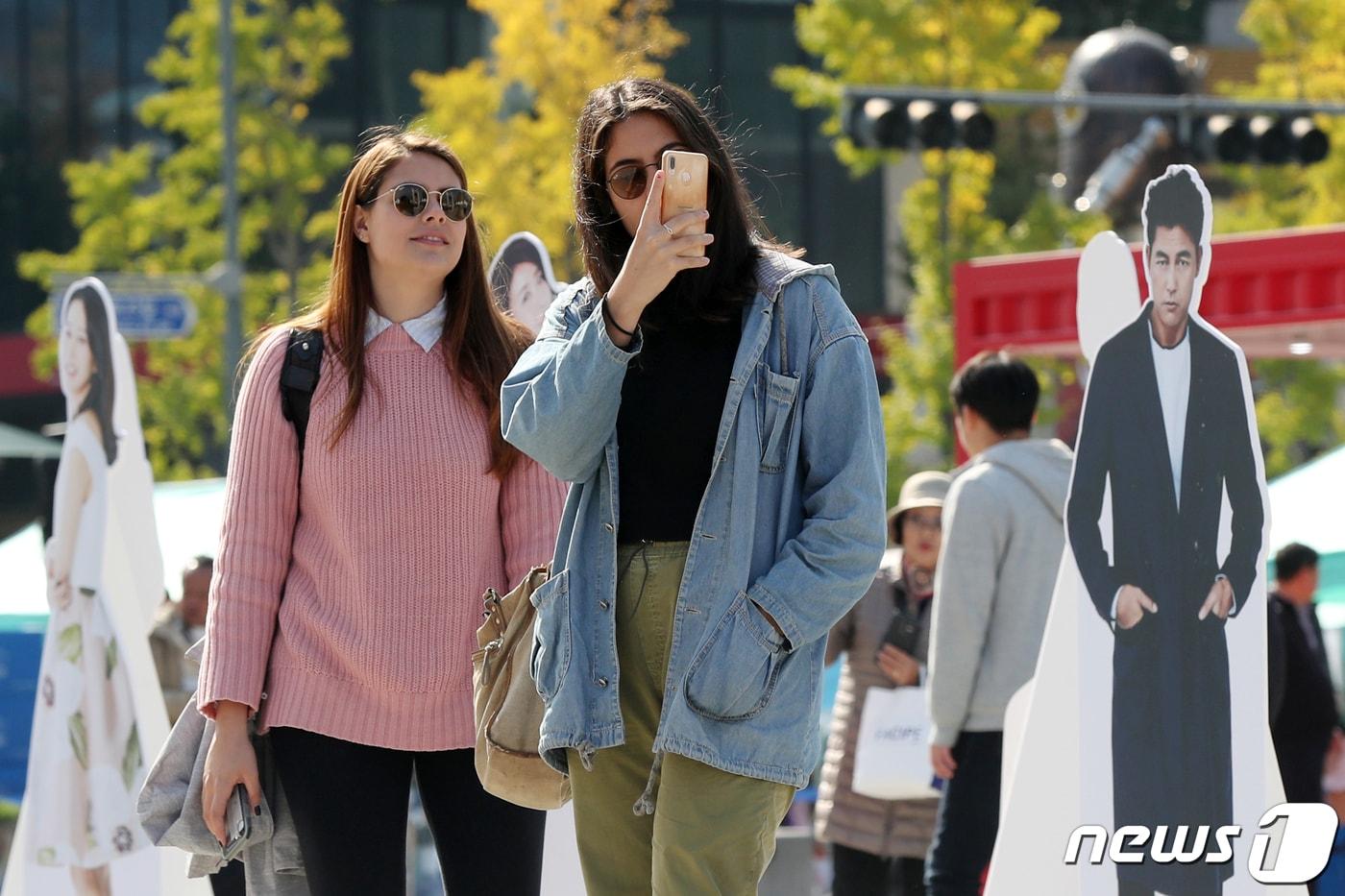 지난해 10월 서울 종로구 광화문광장에 마련된 '한국영화 100년 기념 광화문 축제' 행사장 포토존을 찾은 외국인 관광객들이 우리나라를 대표하는 영화감독과 배우들의 사진 곁에서 기념촬영을 하고 있다. ⓒ News1 민경석 기자
