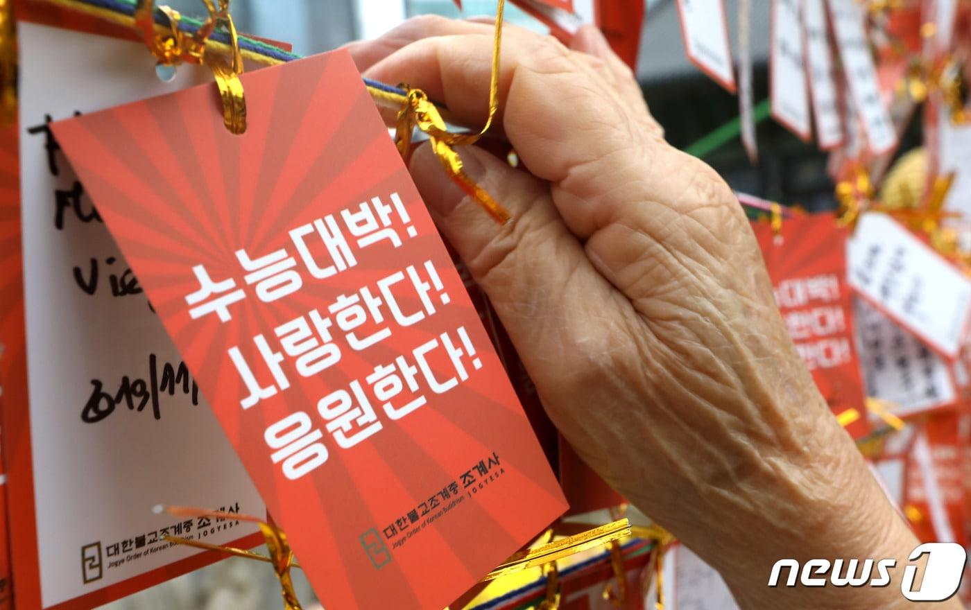 본문 이미지 - 2020학년도 수능시험을 앞두고 지난 10일 서울 종로구 조계사에서 한 할머니가 손자의 학업 성취를 기원하는 문구가 적힌 소원지를 새끼줄에 매달고 있다. ⓒ News1 이동해 기자