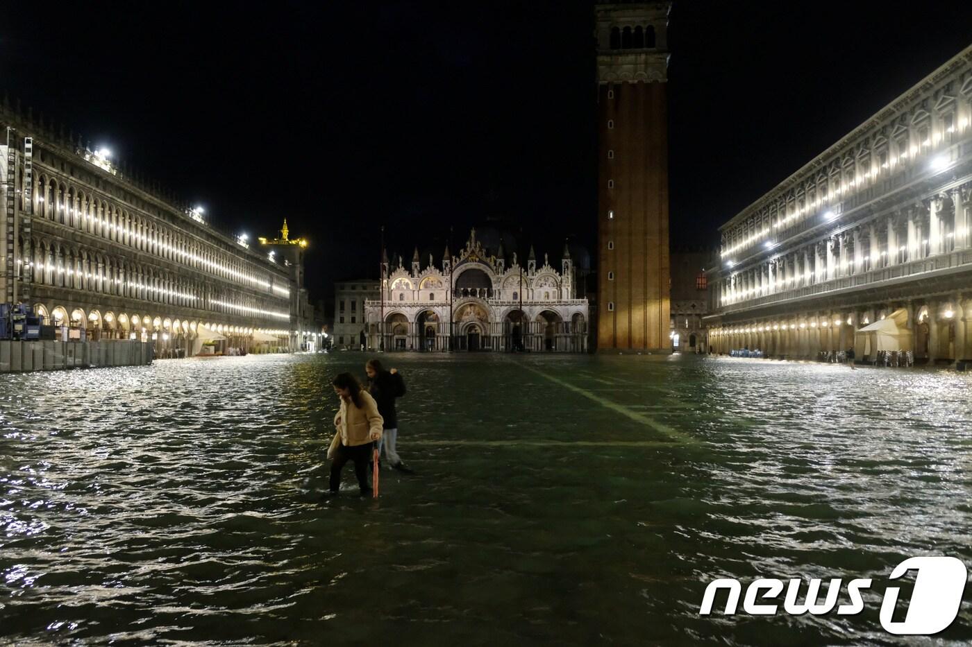 12일(현지시간) 물에 잠긴 이탈리아 베네치아 산마크로 광장을 지나가는 사람들. ⓒ 로이터=뉴스1