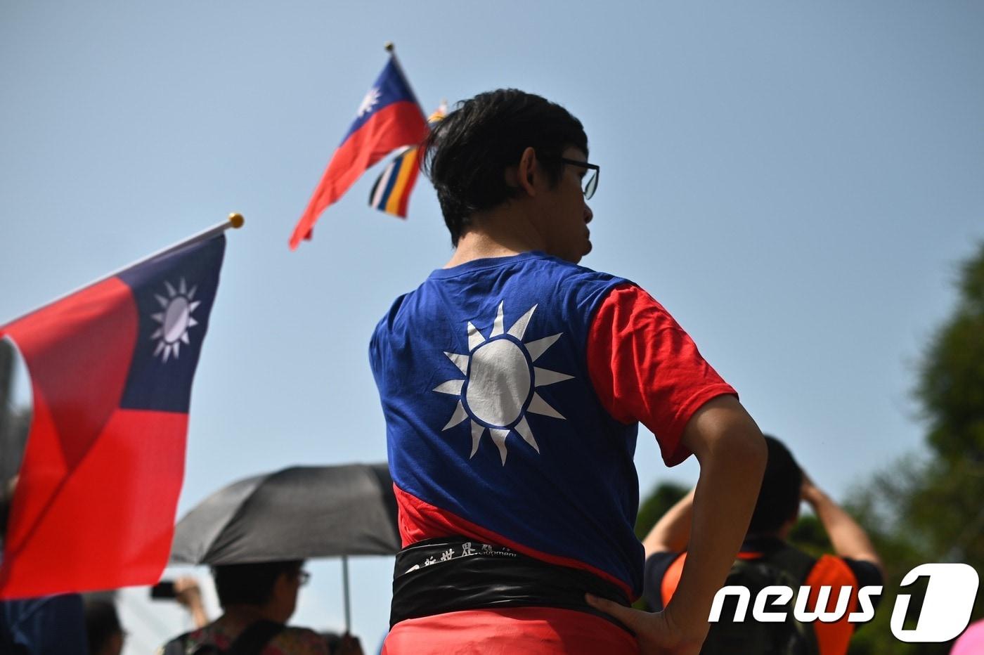 본문 이미지 - 한 남성이 대만 건국 108주년 기념식이 열린 홍콩 툰먼 지역에서 국기 게양식 도중 대만 국기를 들고 있다. ⓒ AFP=뉴스1