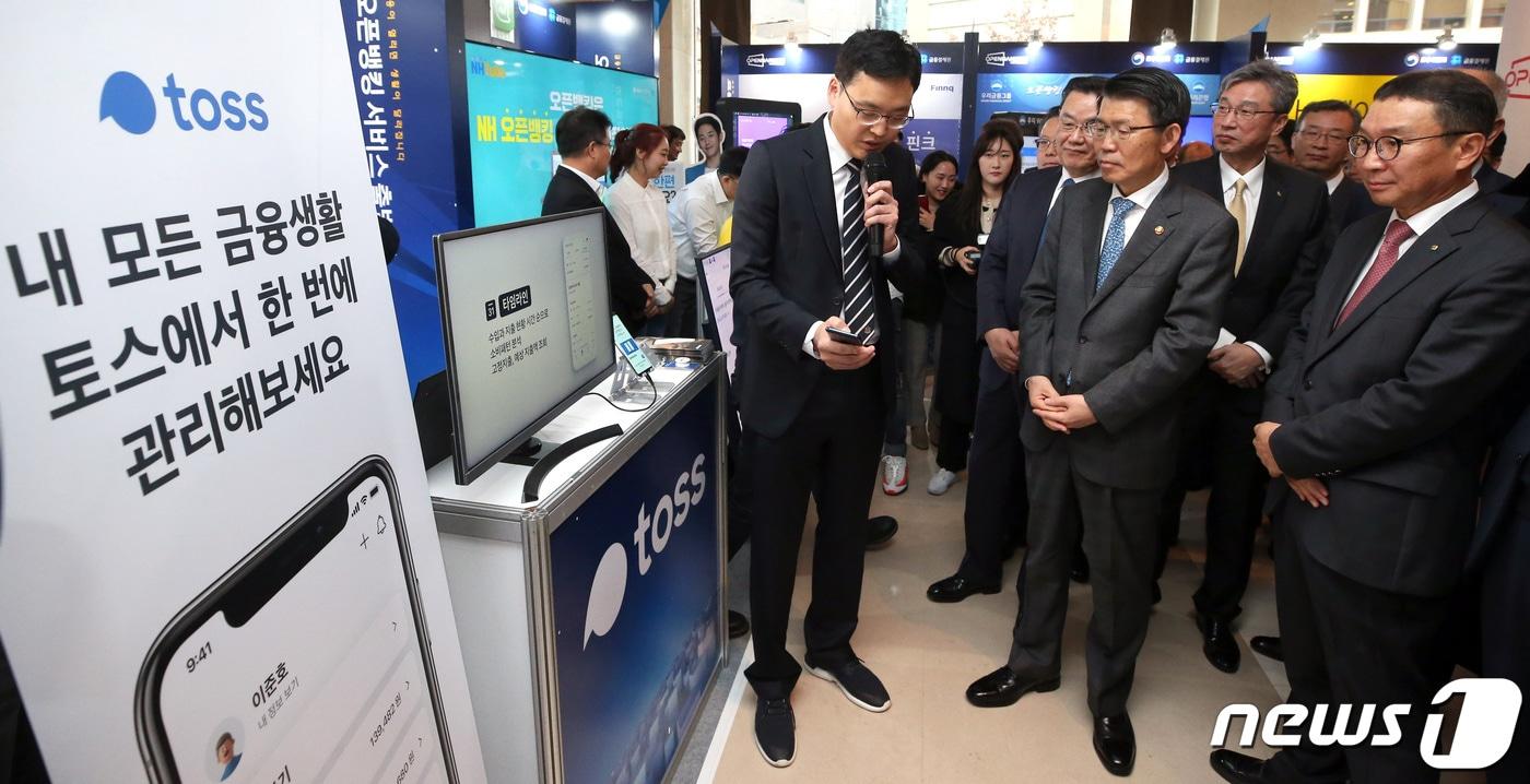 은성수 금융위원장을 비롯한 금융 관계자들이 18일 오전 서울 중구 웨스틴조선호텔에서 열린 ‘오픈뱅킹 서비스 출범식’에 참석해 토스 부스를 방문, 오픈뱅킹 서비스 시연을 보고 있다. 2019.12.18/뉴스1 ⓒ News1 박정호 기자