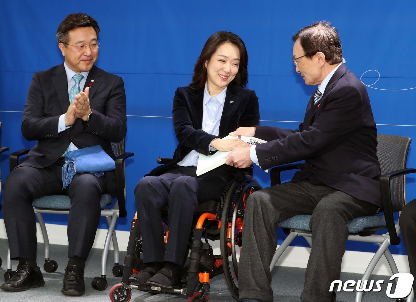 본문 이미지 - 이해찬 더불어민주당 대표가 26일 서울 여의도 더불어민주당 중앙당사에서 21대 총선 인재영입 1호인 발레리나 출신 척수장애인 최혜영 교수에게 민주당 당헌 당규집을 전달하고 있다. 2019.12.26./뉴스1 ⓒ News1 이종덕 기자