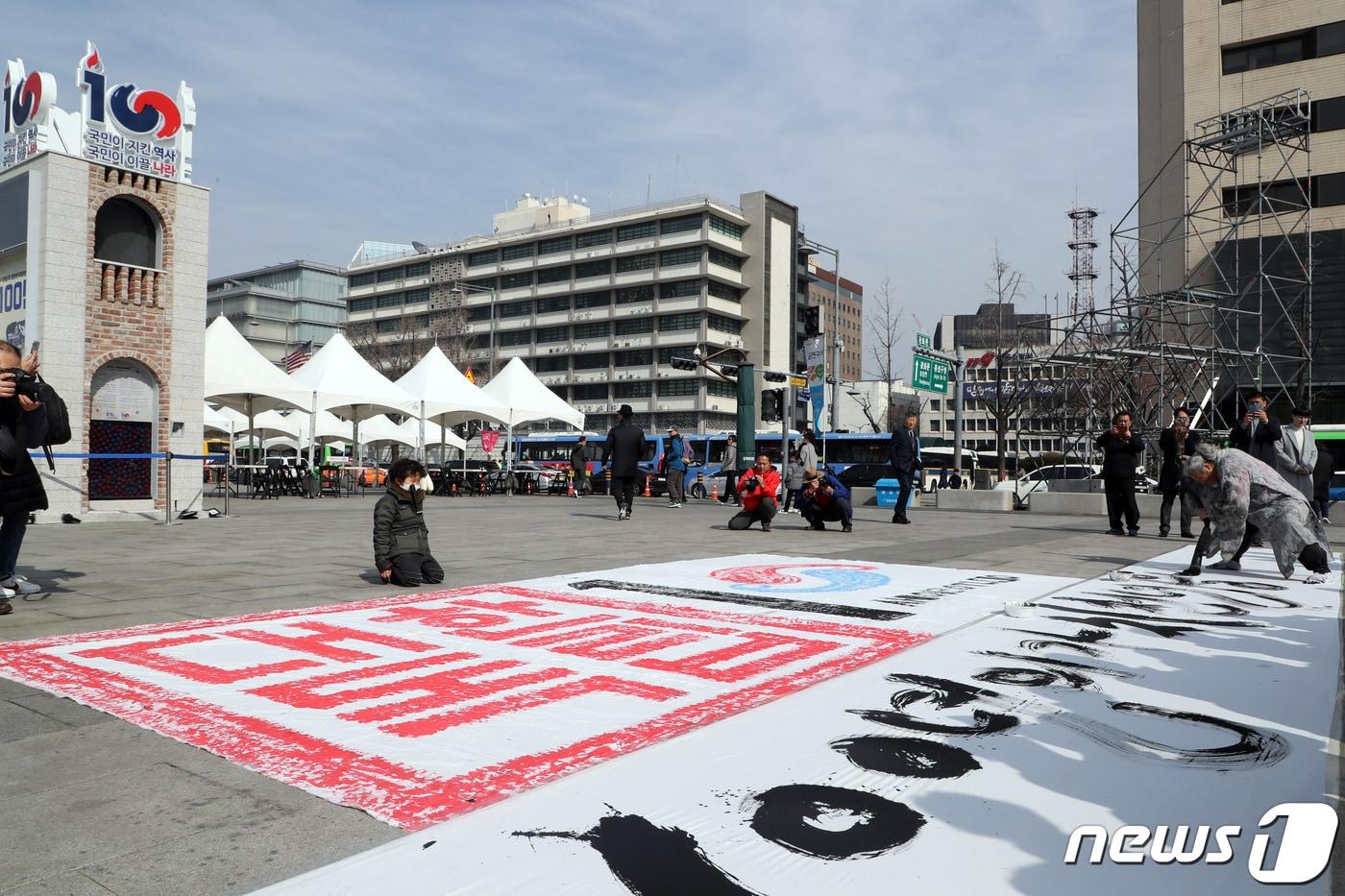 본문 이미지 - 쌍산(雙山) 김동욱 서예가가 25일 오후 서울 광화문광장에서 3.1절 100주년 기념 서예퍼포먼스를 펼치고 있다. 이날 김동욱 서예가는 대형 붓으로 길이 30m 폭1.6m 크기 광목천에 '삼일운동 100년의 가치 천년을 날아오르다'라는 글귀를 적었다. 2019.2.25/뉴스1 ⓒ News1 황기선 기자