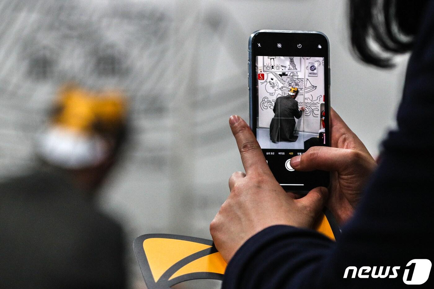 거리 예술가 토마 뷔유가 12일 오후 서울 응암순환 6호선 지하철 객차 안에서 그의 대표 캐릭터인 '무슈샤 웃는 고양이' 그림을 그리는 행위예술을 한 시민이 촬영하고 있다. 2019.3.12/뉴스1 ⓒ News1 성동훈 기자