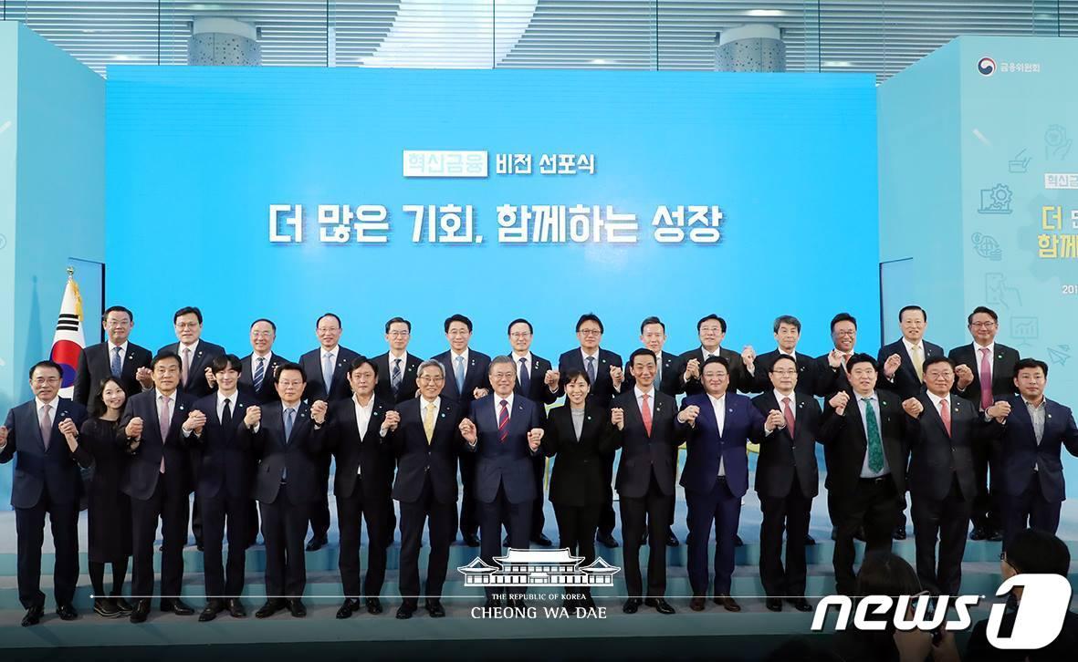 본문 이미지 - 문재인 대통령이 지난해 3월21일 서울 중구 IBK 기업은행 본점에서 열린 혁신금융 비전선포식에서 금융지주 대표, 기업 대표들과 함께 '기업과 금융이 함께 간다'는 의미로 손을 맞잡고 기념촬영하고 있는 모습. (청와대 페이스북) 2019.3.21/뉴스1