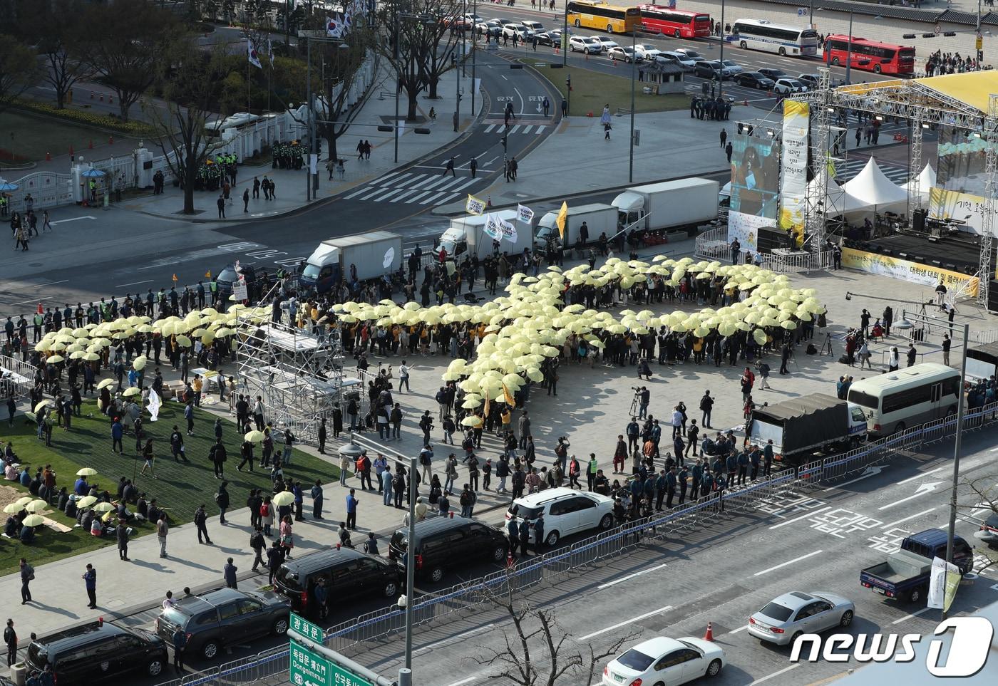본문 이미지 - 14일 오후 4시 16분에 서울 광화문광장에서 열린 세월호 참사 5주기 ‘잊지 않을게’ 대학생 대회에서 참가자들이 노란 우산으로 세월호 리본을 만드는 퍼포먼스를 하고 있다. 2019.4.13/뉴스1 ⓒ News1 신웅수 기자