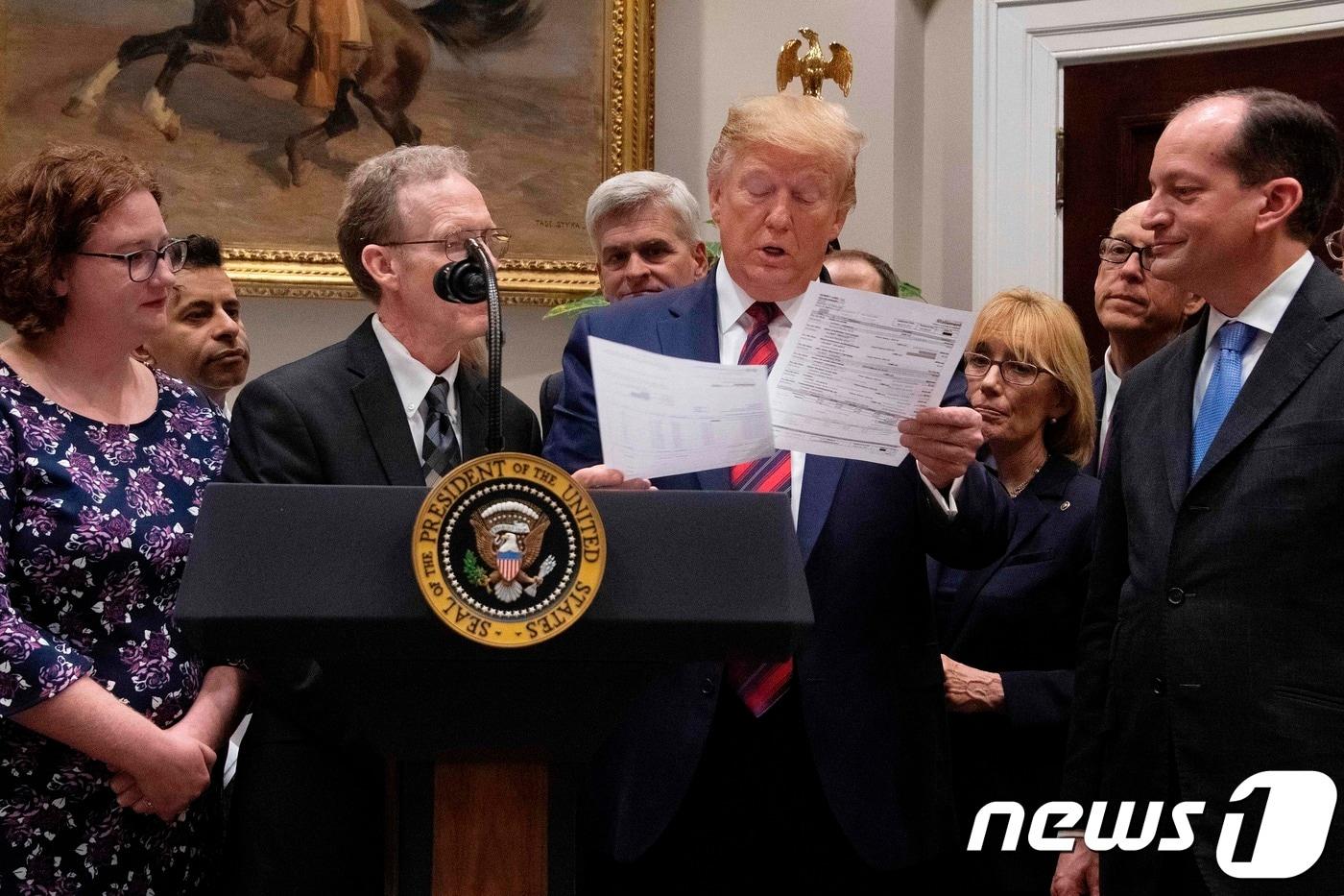 도널드 트럼프 미국 대통령이 9일&#40;현지시간&#41; 워싱턴 백악관에서 열린 &#39;엄청난 의료비 청구서 종료 선언&#39; 행사 중 의료비 청구서룰 보고 있다. ⓒ AFP=뉴스1 ⓒ News1 우동명 기자