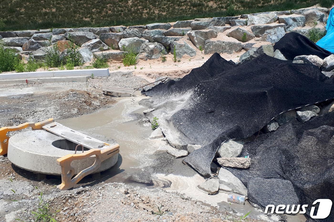 도로 공사현장에 검은 천막 아래 건설폐기물이 방치돼 있고 웅덩이에는 레미콘과 물이 섞인채 고여 있다. 2019.7.2/뉴스1 ⓒ News1 김경석 기자