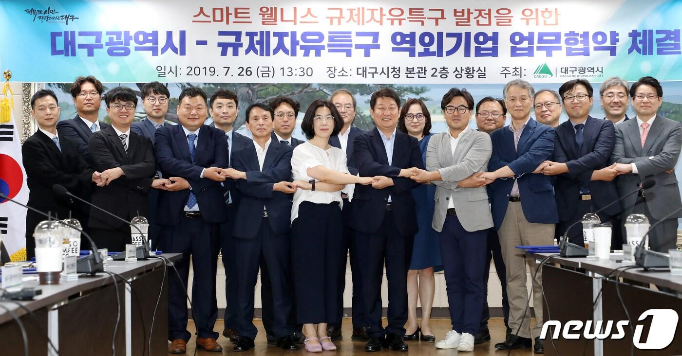 본문 이미지 - 26일 오후 대구시청 본관 상황실에서 열린 '대구시-규제자유특구 역외기업 업무협약 체결식'에서 권영진 대구시장과 대구 스마트 웰니스 규제자유특구에 참여하는 역외유치 특구사업자 14개 기업(스마트 임상·웰니스 정보서비스·공동제조소) 대표 등 참석자들이 손을 맞잡고 있다. 2019.7.26/뉴스1 ⓒ News1 공정식 기자