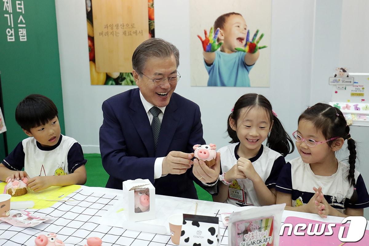본문 이미지 - 문재인 대통령이 지난 2019년 7월 제2회 대한민국 사회적경제 박람회 전시관을 방문, 어린이들과 '슈가클레이'를 이용한 컵케이크를 만들고 있다. (청와대 제공) 2019.7.5/뉴스1