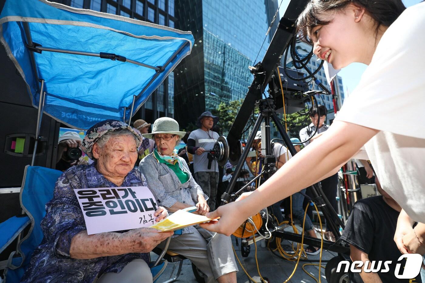 본문 이미지 - 14일 서울 종로구 중학동 옛 일본대사관 앞에서 열린 제1400차 일본군 성노예제 문제 해결을 위한 정기 수요시위에서 길원옥 할머니가 광주 조선대학교 부속 여자고등학교 학생들의 편지를 받고 있다. 2019.8.14/뉴스1 ⓒ News1 박정호 기자
