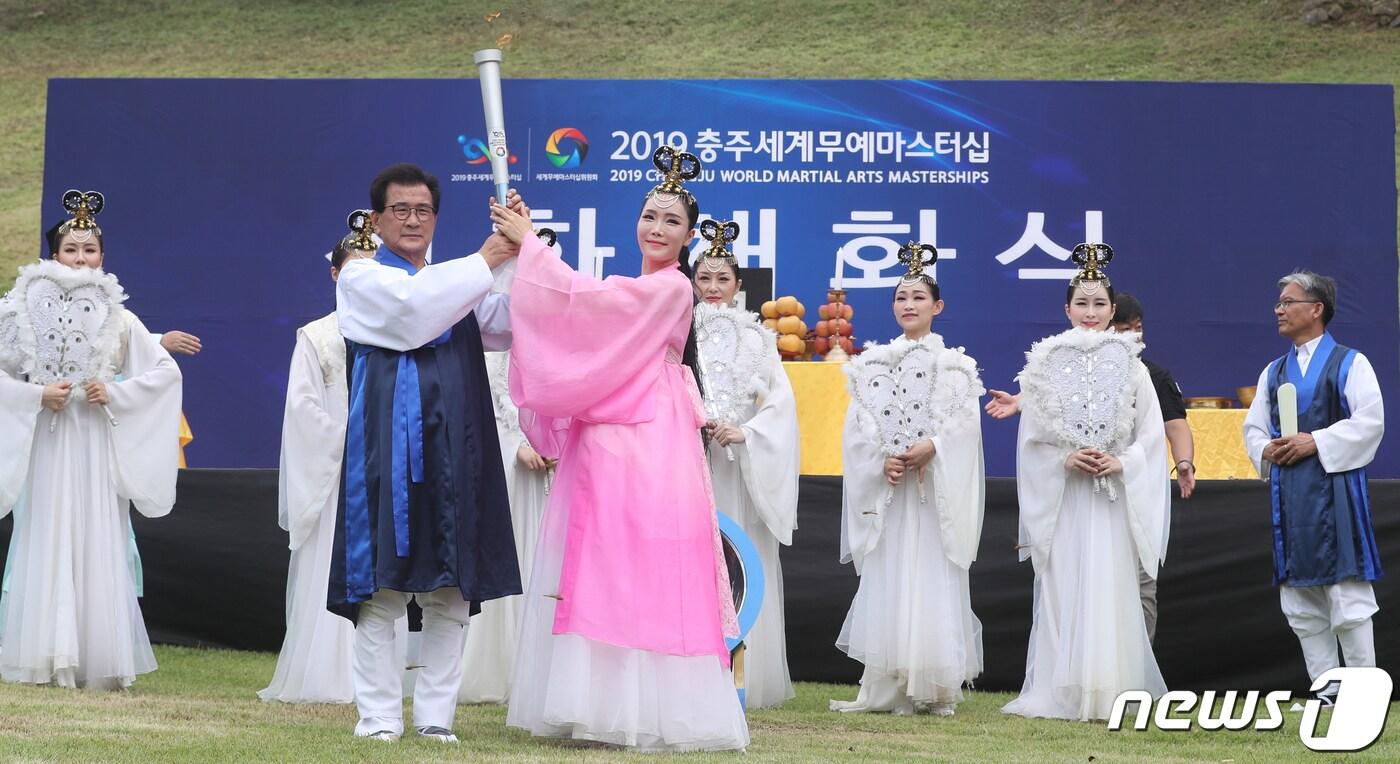 본문 이미지 - 28일 오전 충북 청주시 상당산성 남문에서 열린 2019충주세계무예마스터십 성화 채화식에서 공동조직위원장인 이시종 충북지사가 주선녀로부터 성화를 건네받고 있다. 2019.8.28/뉴스1 ⓒ News1 김용빈 기자