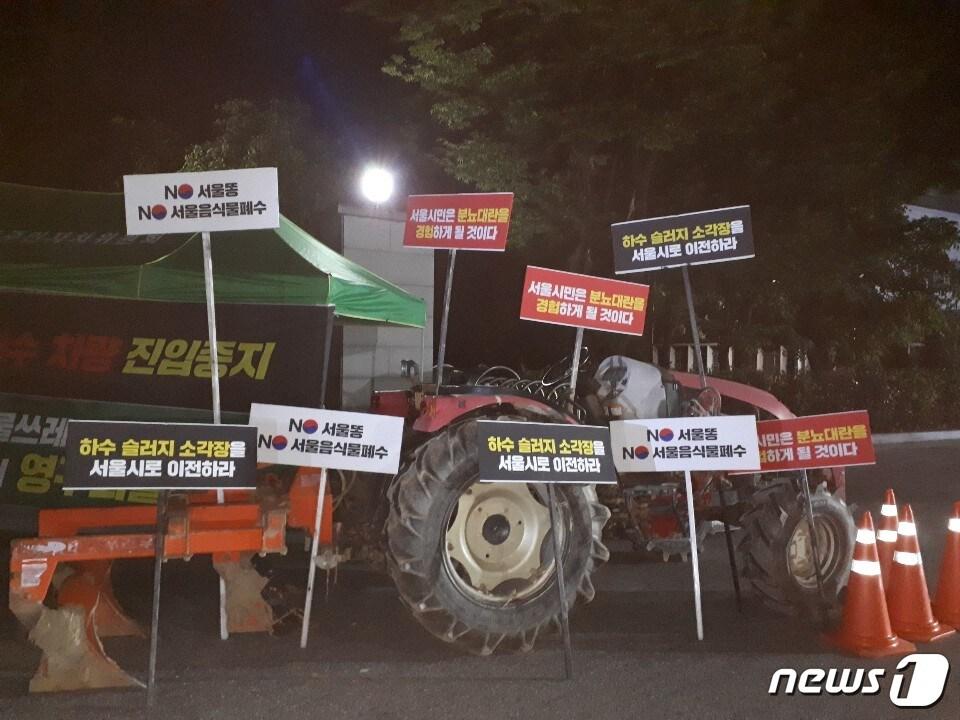 본문 이미지 - 고양시 대덕동 주민들이 지난 19일부터 서울시의 난지물재생센터 차량 출입을 통제하고 있다. 시설에 차량 진출입을 막기 위해 출입문을 막고 있는 주민들의 차량과 피켓. ⓒ 뉴스1