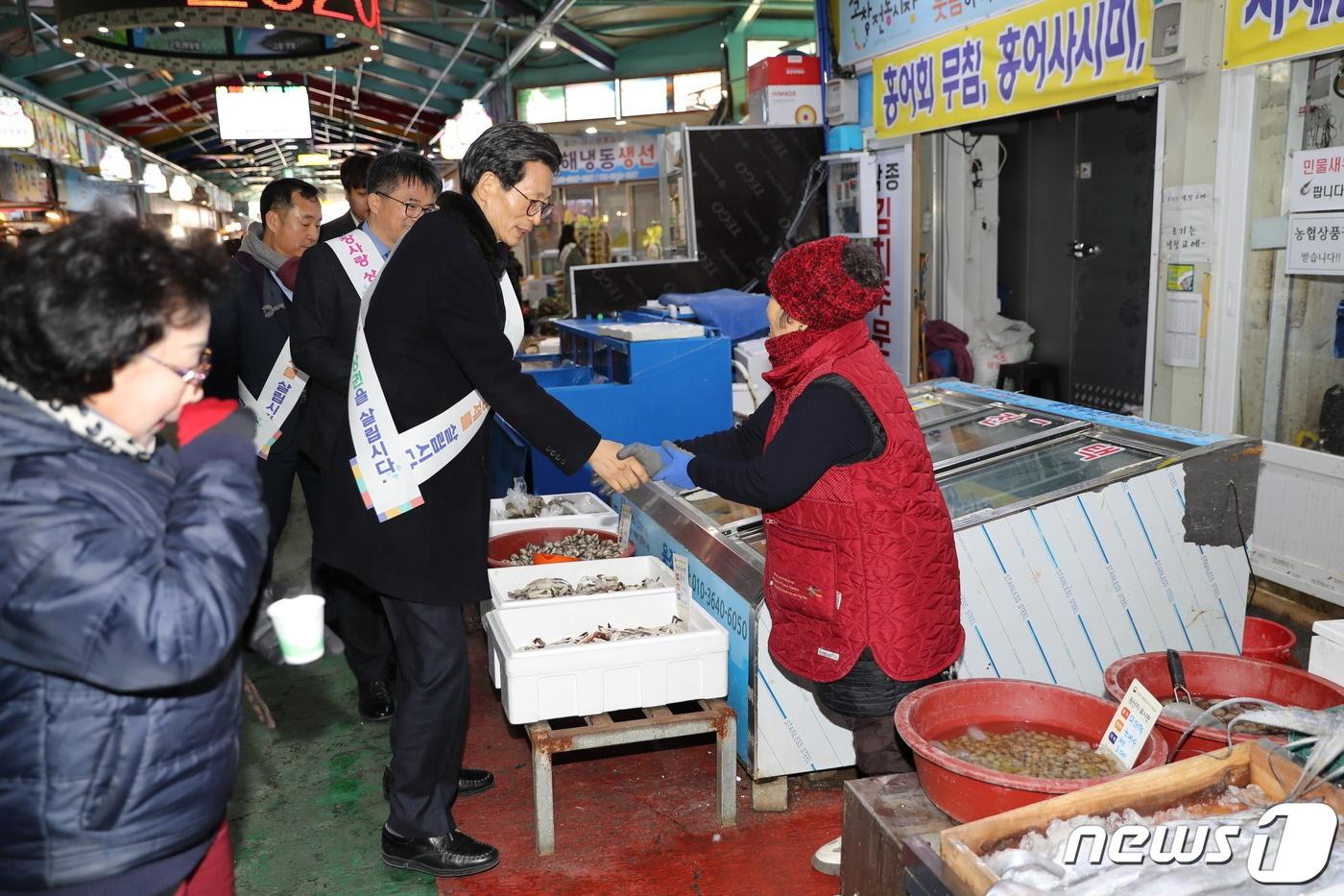 본문 이미지 - 전북 고창군은 21일 설을 앞두고 전통시장과 지역경제 활성화를 위해 ‘설 명절 전통시장 장보기 행사’를 열었다.  유기상 군수가 전통시장 상인과 악수하고 있다. /ⓒ 뉴스1