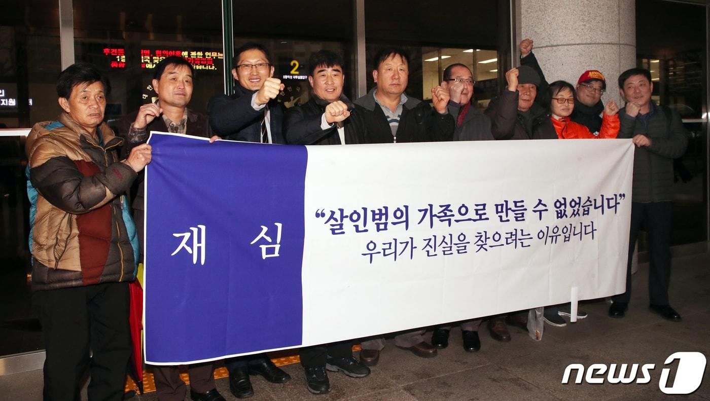 본문 이미지 - ‘낙동강변 살인사건’ 범인으로 지목돼 21년간 옥살이를 한 장동익씨(61·왼쪽 네번째)와 최인철씨(58·왼쪽 다섯번째)가 지난 6일 부산 연제구 부산고법 301호에서 열린 재심 재판을 마친 후 가족들과 플래카드 앞에서 파이팅을 외치고 있다. 2020.1.6 /뉴스1 ⓒ News1 여주연 기자