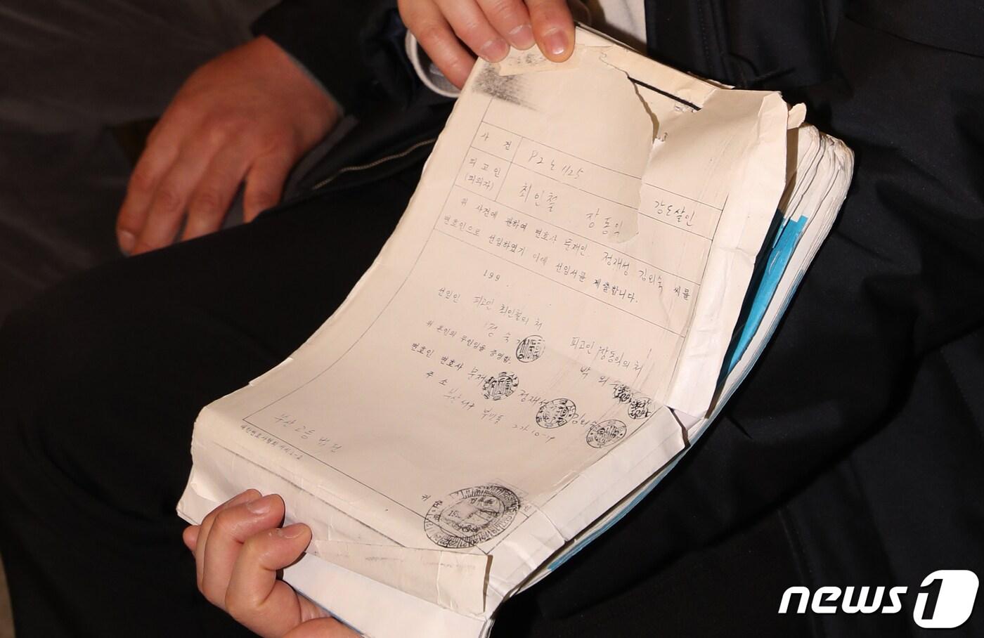 본문 이미지 - ‘낙동강변 살인사건’ 범인으로 지목돼 21년간 옥살이를 한 장동익씨와 최인철씨가 지난해 1월 부산 연제구 부산고법 301호에서 열린 재심 재판에 앞서 취재진에게 당시 변호사 선임 서류를 공개하고 있다. 2020.1.6/뉴스1 ⓒ News1 여주연 기자