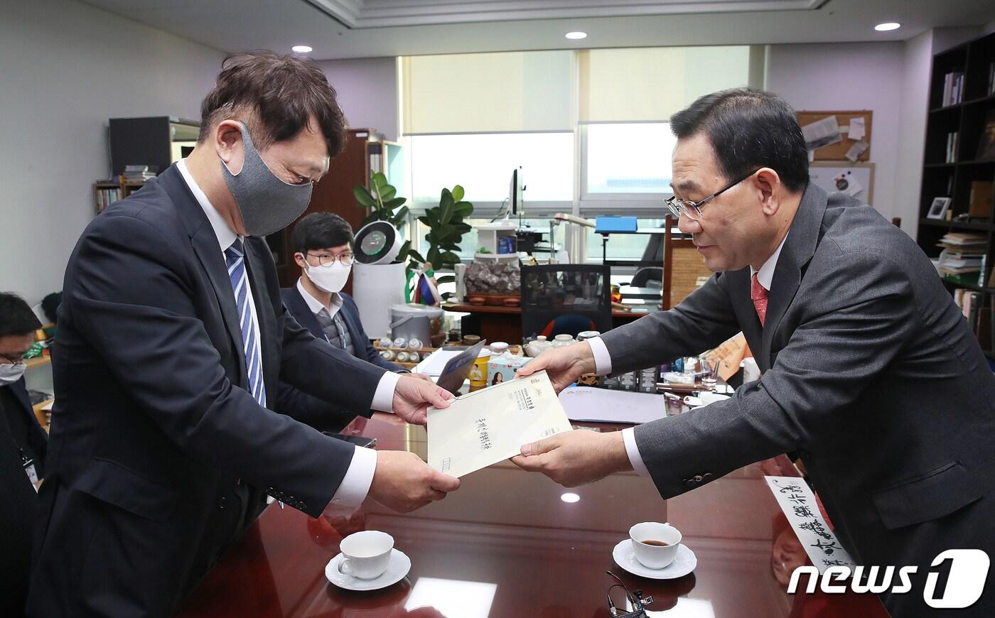 본문 이미지 - 주호영 국민의힘 원내대표(오른쪽)가 26일 서울 여의도 국회 의원회관 사무실에서 최재성 청와대 정무수석에게 '다시 대통령에게 드리는 10가지 질문'이라고 써진 서신을 넣은 서류봉투를 전달하고 있다. 2020.10.26/뉴스1 ⓒ News1 박세연 기자