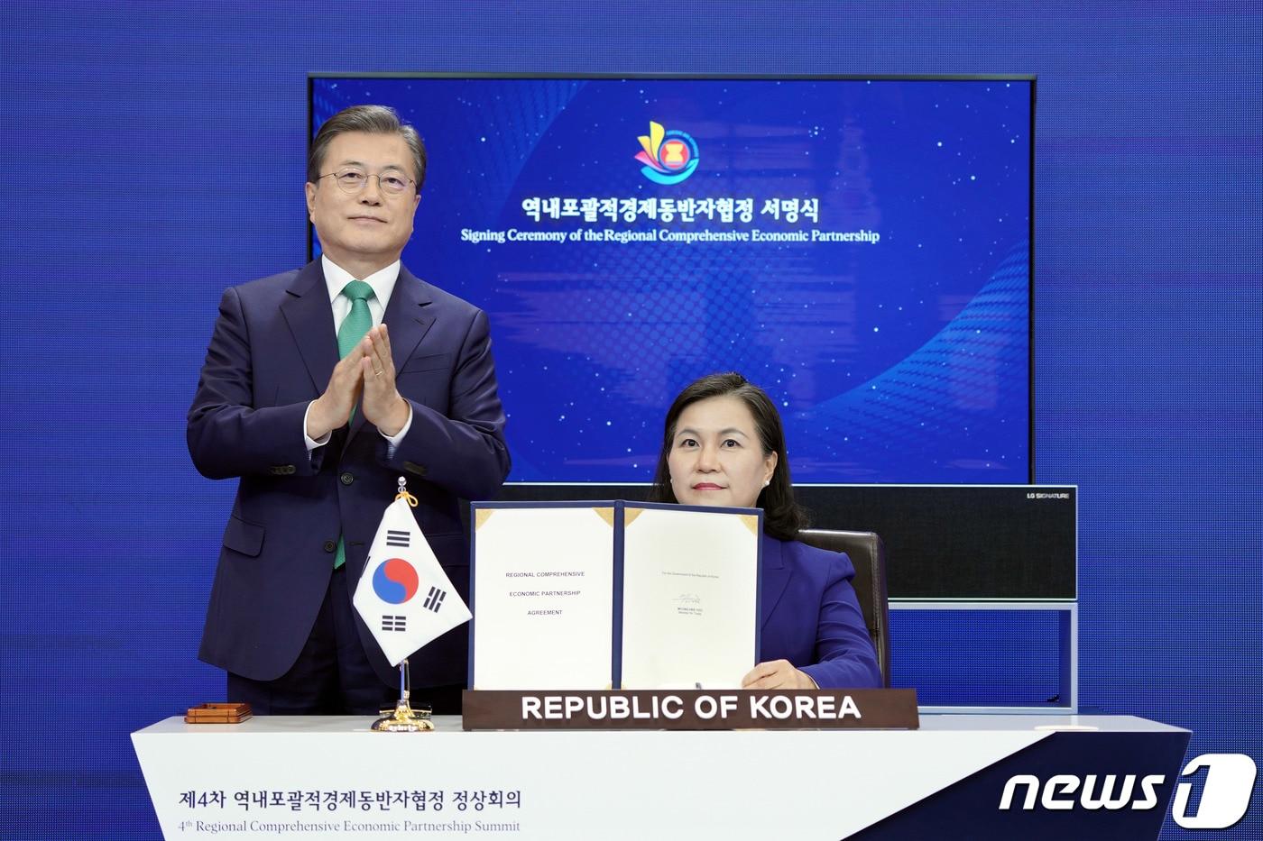 본문 이미지 - 문재인 대통령이 15일 청와대에서 화상회의로 진행된 제4차 역내포괄적경제동반자협정 정상회의 및 협정 서명식에서 협정문에 서명한 유명희 통상교섭본부장 옆에서 박수를 보내고 있다. 2020.11.15/뉴스1 ⓒ News1 박정호 기자