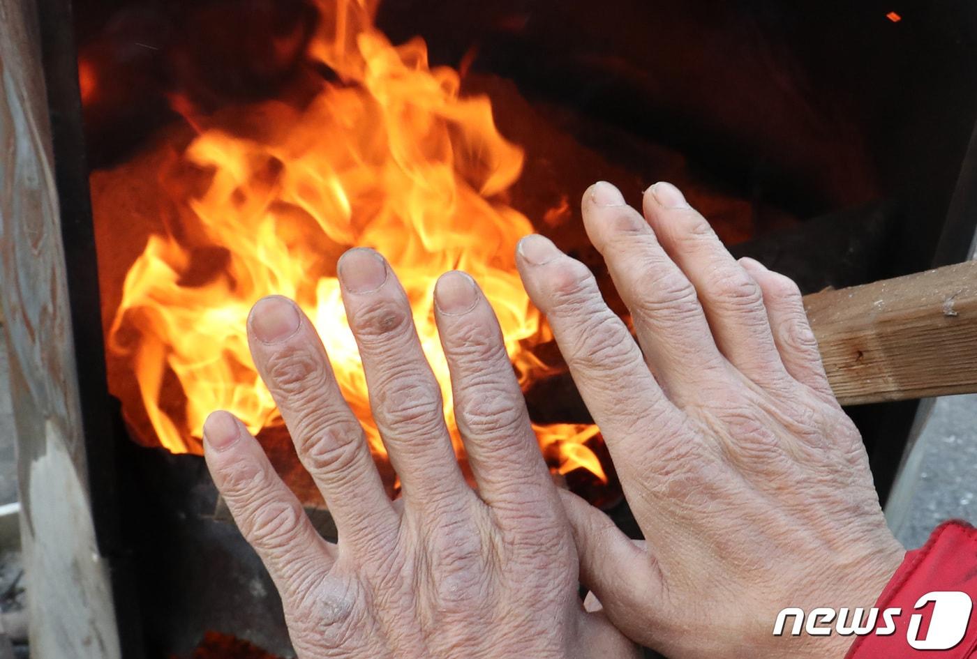 본문 이미지 - 30일 대전·충남은 아침 기온이 -10도 안팎의 강추위가 이어질 것으로 예보됐다. 대전 유성구 노은농수산물도매시장에서 상인이 모닥불로 추위를 녹이고 있다. /뉴스1 ⓒ News1 김기태 기자