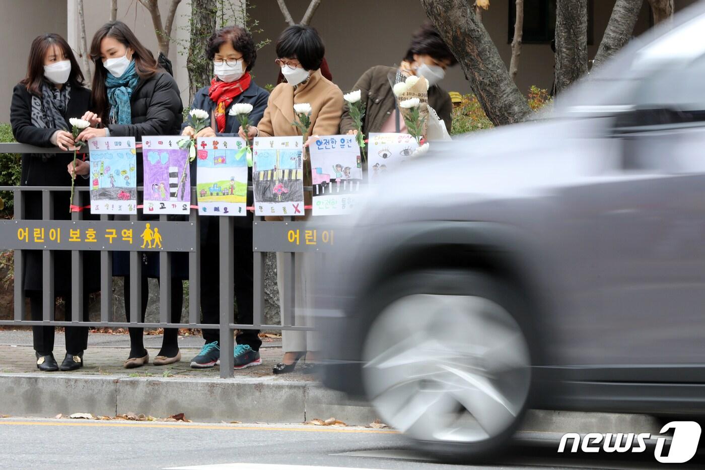 본문 이미지 - 23일 광주 북구 운암동 한 어린이보호구역에서 운암1동행정복지센터 직원들이 최근 해당 구역에서 교통사고로 숨진 3살 여아를 추모하며 안전펜스에 국화를 걸고 있다. 해당 어린이보호구역에서는 지난 17일 오전 8시43분쯤 50대 A씨가 몰던 8.5t 화물차 횡단보도에 서 있던 일가족 4명을 들이받아 3살 여아가 숨지고, 7살 여아와 30대 어머니가 중상을 입는 사고가 발생했다. 2020.11.23/뉴스1 ⓒ News1 황희규 기자