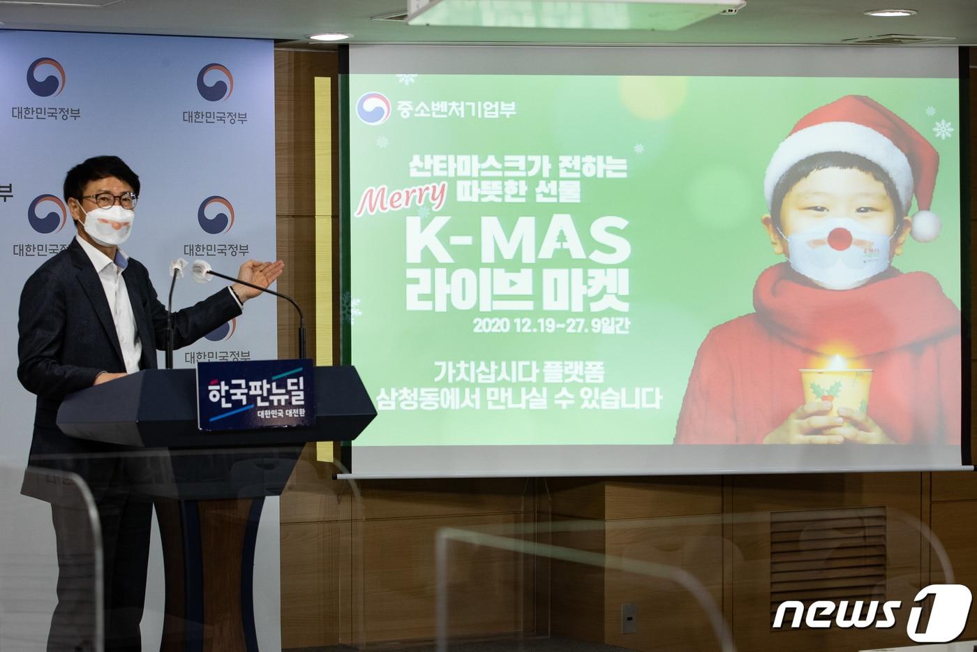 본문 이미지 - 박치형 중소벤처기업부 소상공인정책관이 14일 서울 종로구 정부서울청사 브리핑룸에서 산타마스크를 쓰고 올해 크리스마스 마켓 '2020 K-Mas 라이브마켓' 을 소개하며 아역배우 김준이 출연한 포스터를 선보이고 있다. 2020.12.14/뉴스1 ⓒ News1 유승관 기자