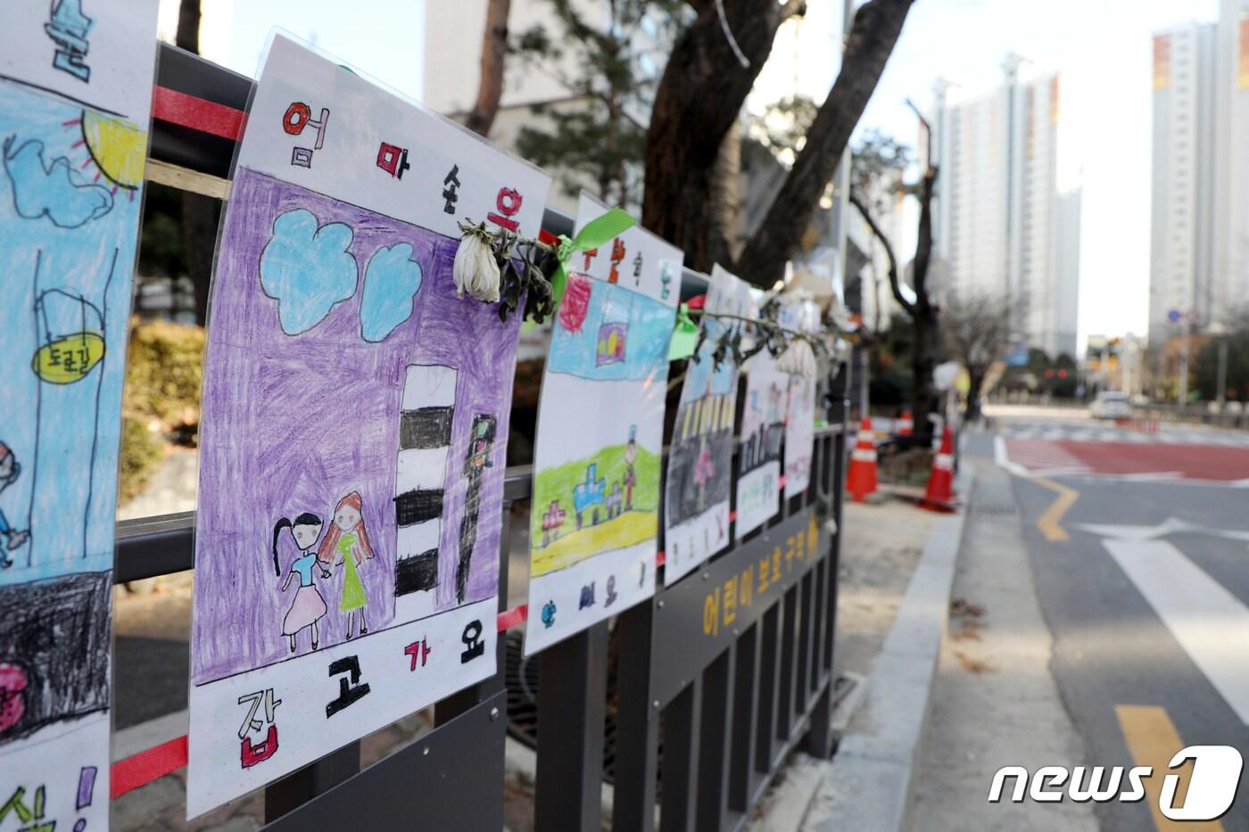 본문 이미지 - 15일 오전 광주 북구 운암동 스쿨존 교통사고 현장에 시든 국화꽃과 함께 아이들이 그린 교통캠페인 포스터가 걸려 있다.2020.12.15/뉴스1 ⓒ News1 허단비 기자