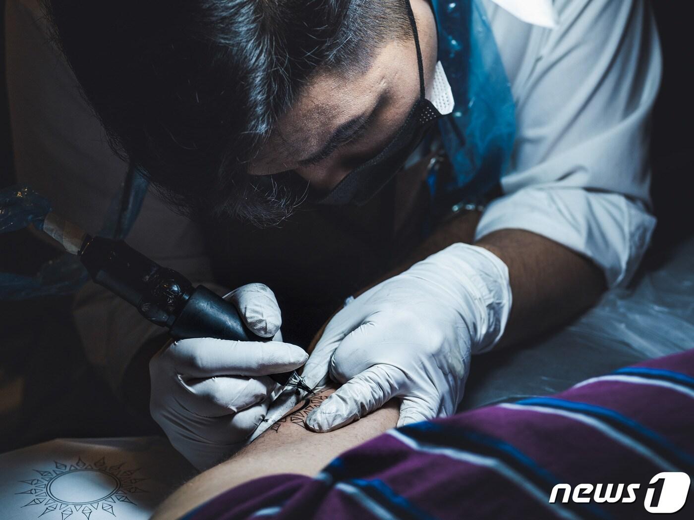 본문 이미지 - 타투이스트 이유철씨가 고객의 몸에 문신을 새겨 넣고 있다. (노마드 스튜디오 제공)ⓒ 뉴스1