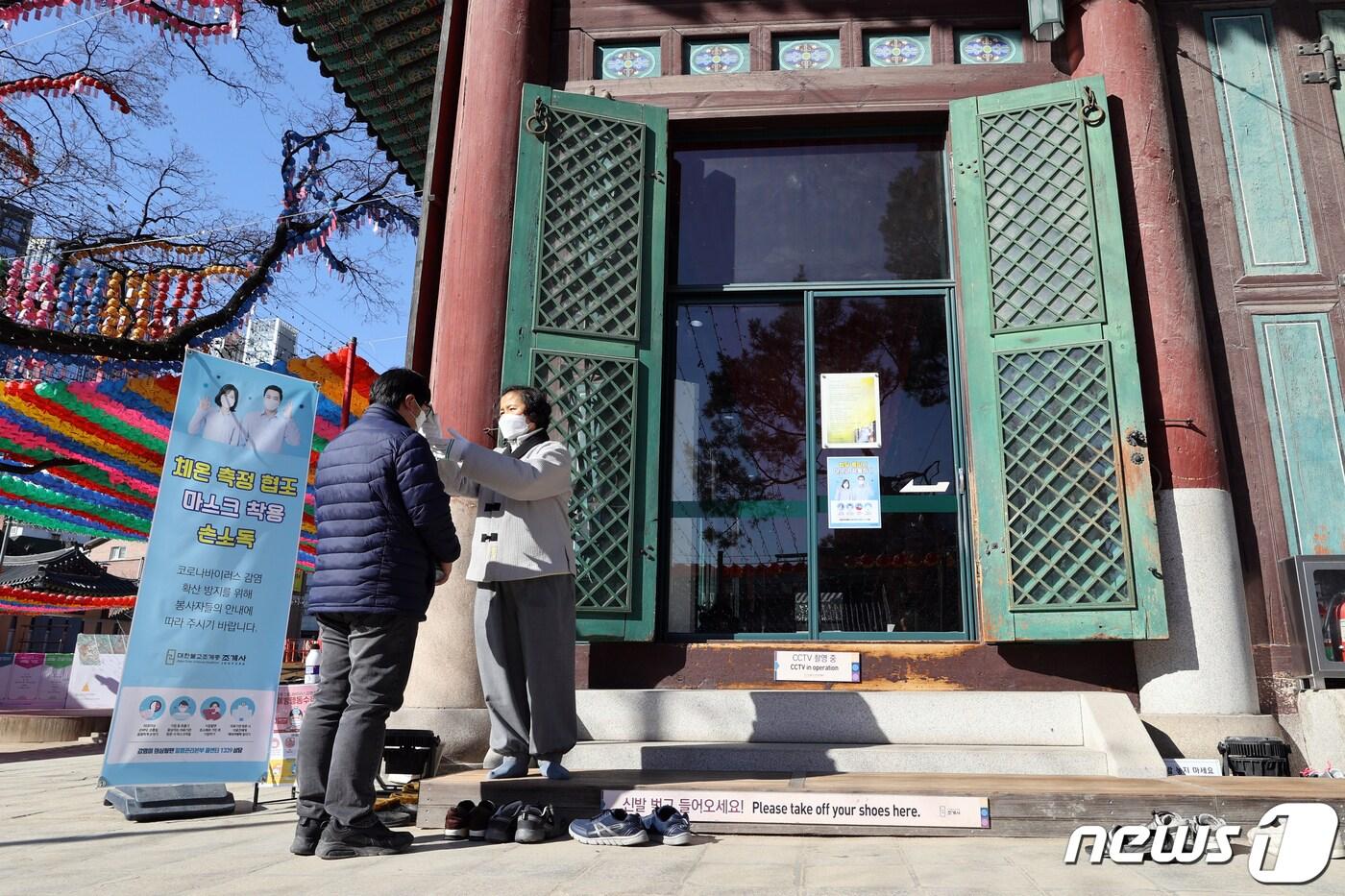 23일 오전 서울 종로구 조계사에서 한 신도가 체온 측정을 받고 있다. 조계사는 신종 코로나바이러스 감염증(코로나19) 확산과 관련 이날 예정된 일요법회를 법문없이 기도로만 진행했다. 2020.2.23/뉴스1 ⓒ News1 안은나 기자