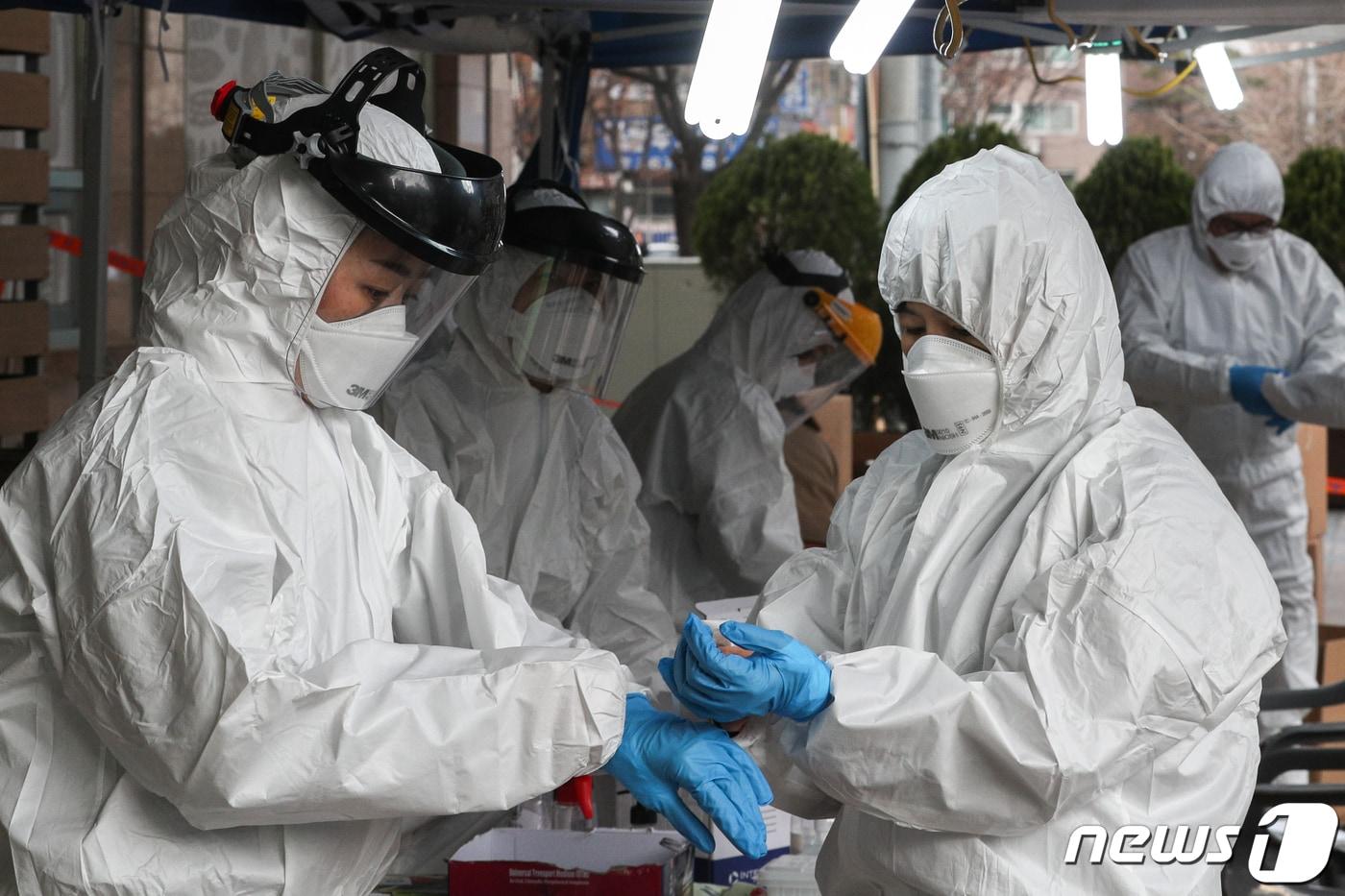 구로구 신도림동 콜센터에서 신종 코로나바이러스 감염증(코로나19) 집단감염이 발생한 가운데 13일 오전 콜센터가 위치한 서울 코리아빌딩 앞 선별진료소에서 구로구 보건소 관계자들이 코로나19 검진을 위해 방호복을 입고 있다. 2020.3.12/뉴스1 ⓒ News1 성동훈 기자