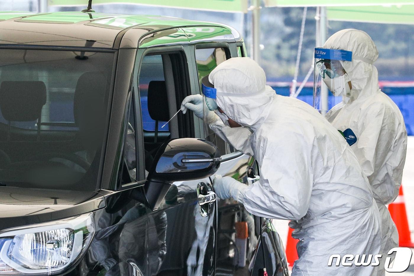 24일 서울 송파구 잠실종합운동장 주경기장에 설치된 신종 코로나바이러스 감염증(코로나19) 서울시 승차검진 선별진료소에서 시민들이 차량에 탄 채 검사를 받고 있다. 20203.24/뉴스1 ⓒ News1 성동훈 기자