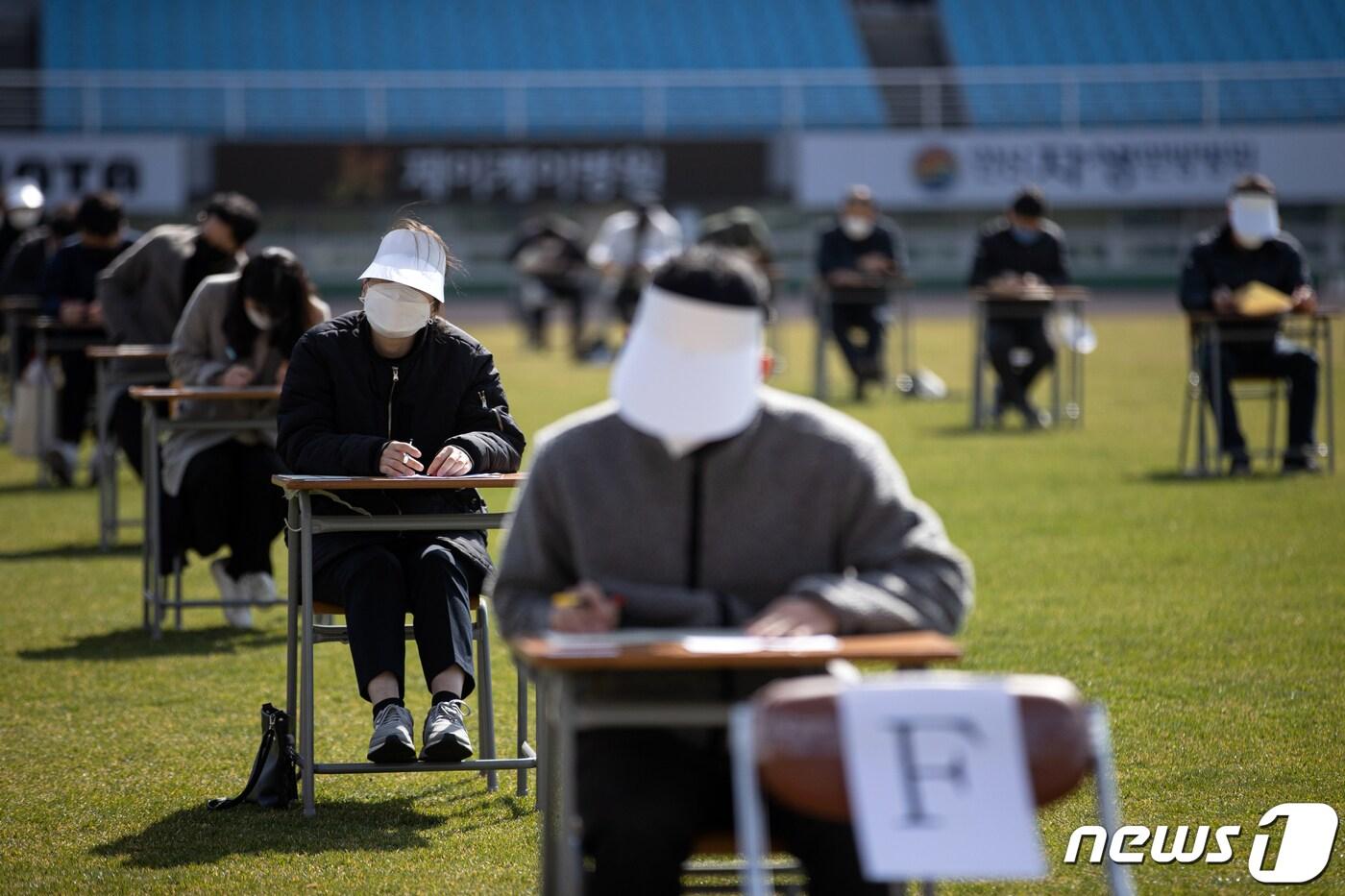 4일 오전 경기도 안산시 단원구 안산와스타디움에서 열린 안산도시공사 상반기 공개채용 야외 필기시험에서 응시자들이 시험 시작을 기다리고 있다. 시험이 치러지는 와스타디움은 2,000평 규모의 종합운동장으로 공사는 스타디움내 천연 잔디 축구장에 신종 코로나바이러스 감염증(코로나19)로 인한 사회적 거리 두기 일환으로 140여개의 책걸상을 사방 5m 간격으로 배치하고, 응시자들은 마스크를 착용하고 발열 측정과 손소독 등 방역을 거친 뒤 시험장에 입장해 시험을 실시했다. ⓒ News1 이승배 기자