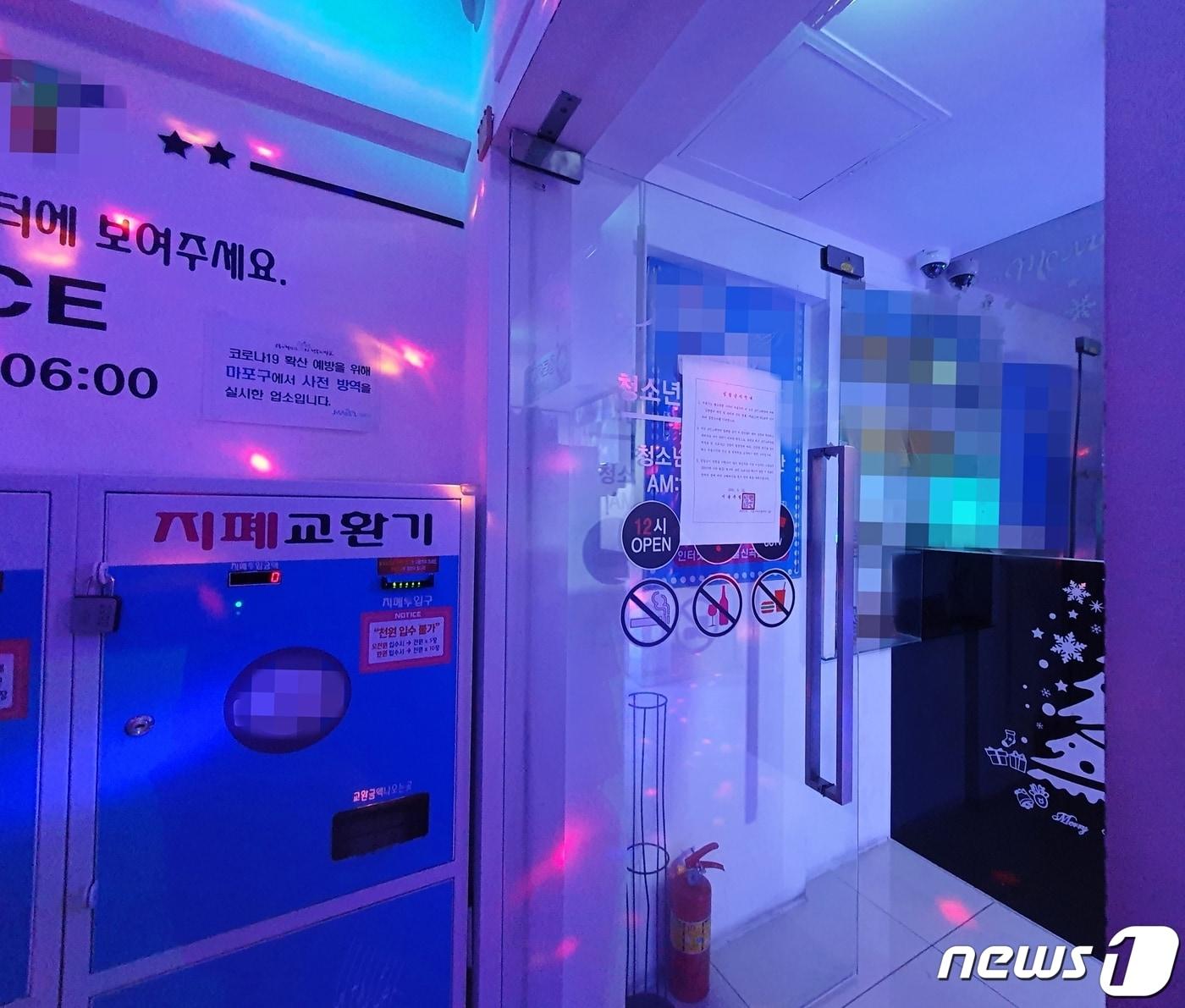 본문 이미지 - 박원순 서울시장이 시내 모든 코인노래연습장(코인노래방) 집합금지 행정명령을 내린 22일 밤 서울 마포구 홍익대 앞 번화가의 한 코인노래연습장이 성업 중이다. 정문에는 서울특별시장 직인이 찍힌 집합금지안내문이 붙어있다. 2020.5.23/뉴스1 ⓒ News1 황덕현 기자